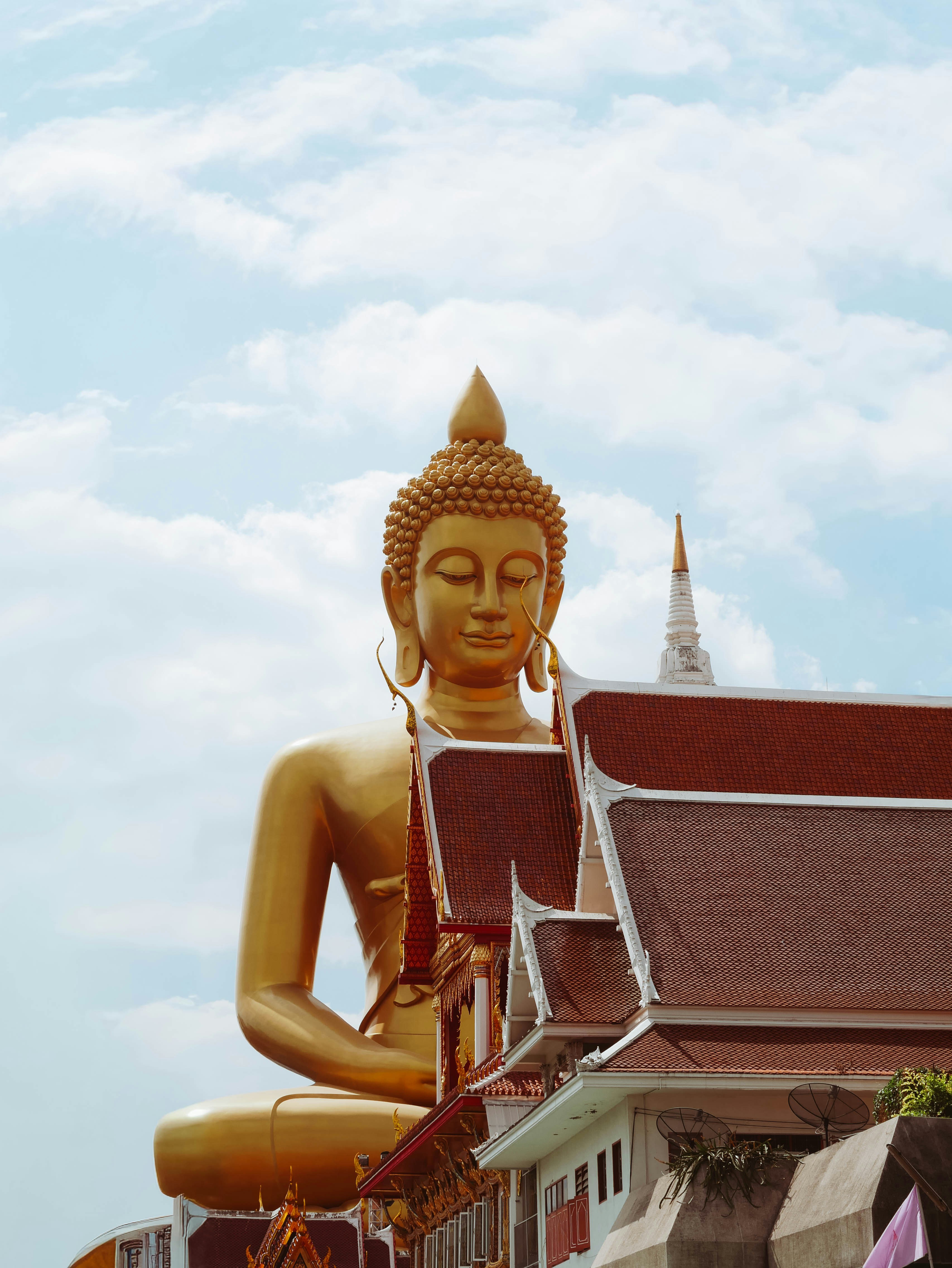 A large golden buddha statue against a cloudy sky.