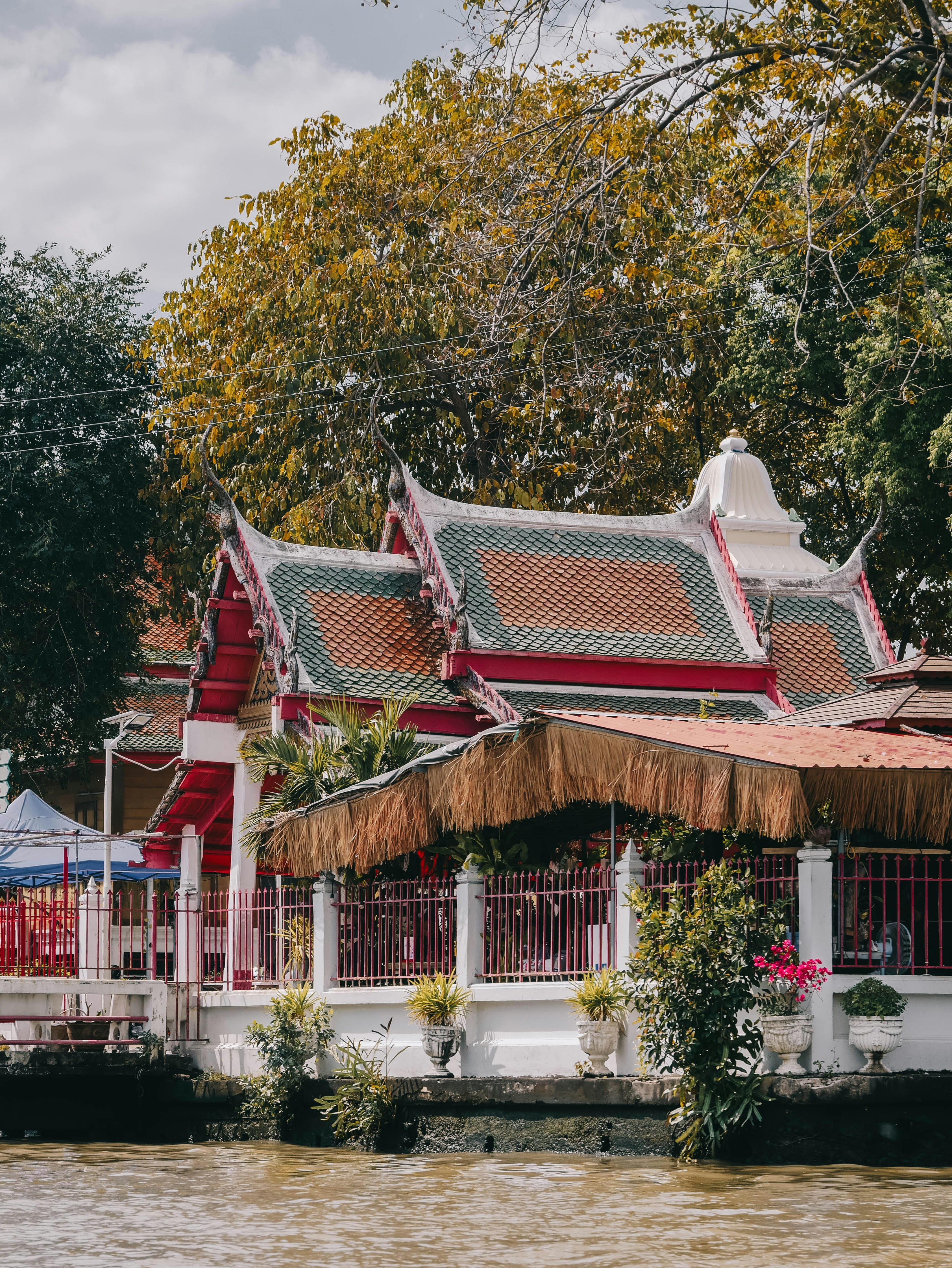 Traditional thai temple with ornate roofs and lush trees.