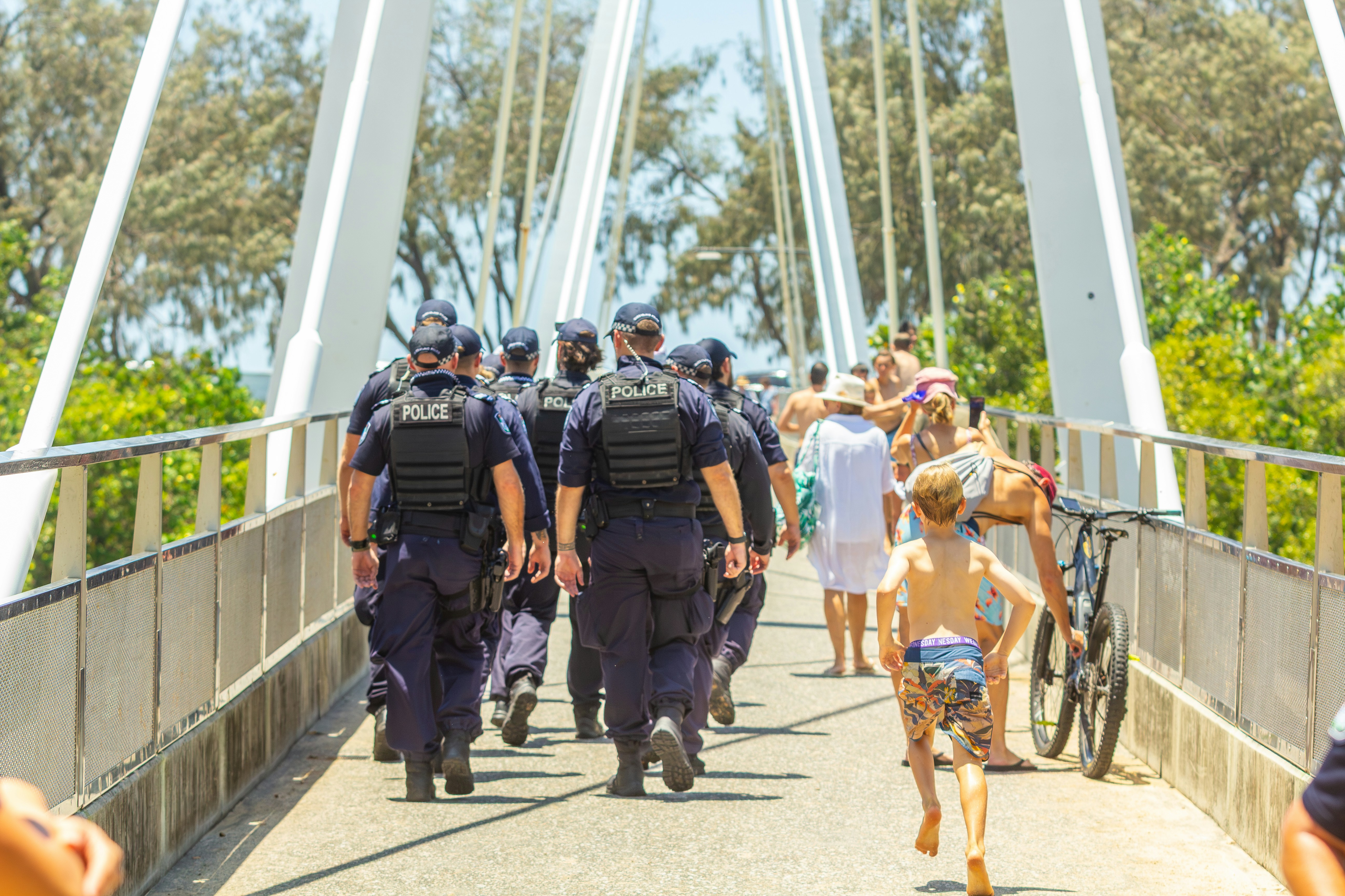 Police officers walk on a bridge with civilians