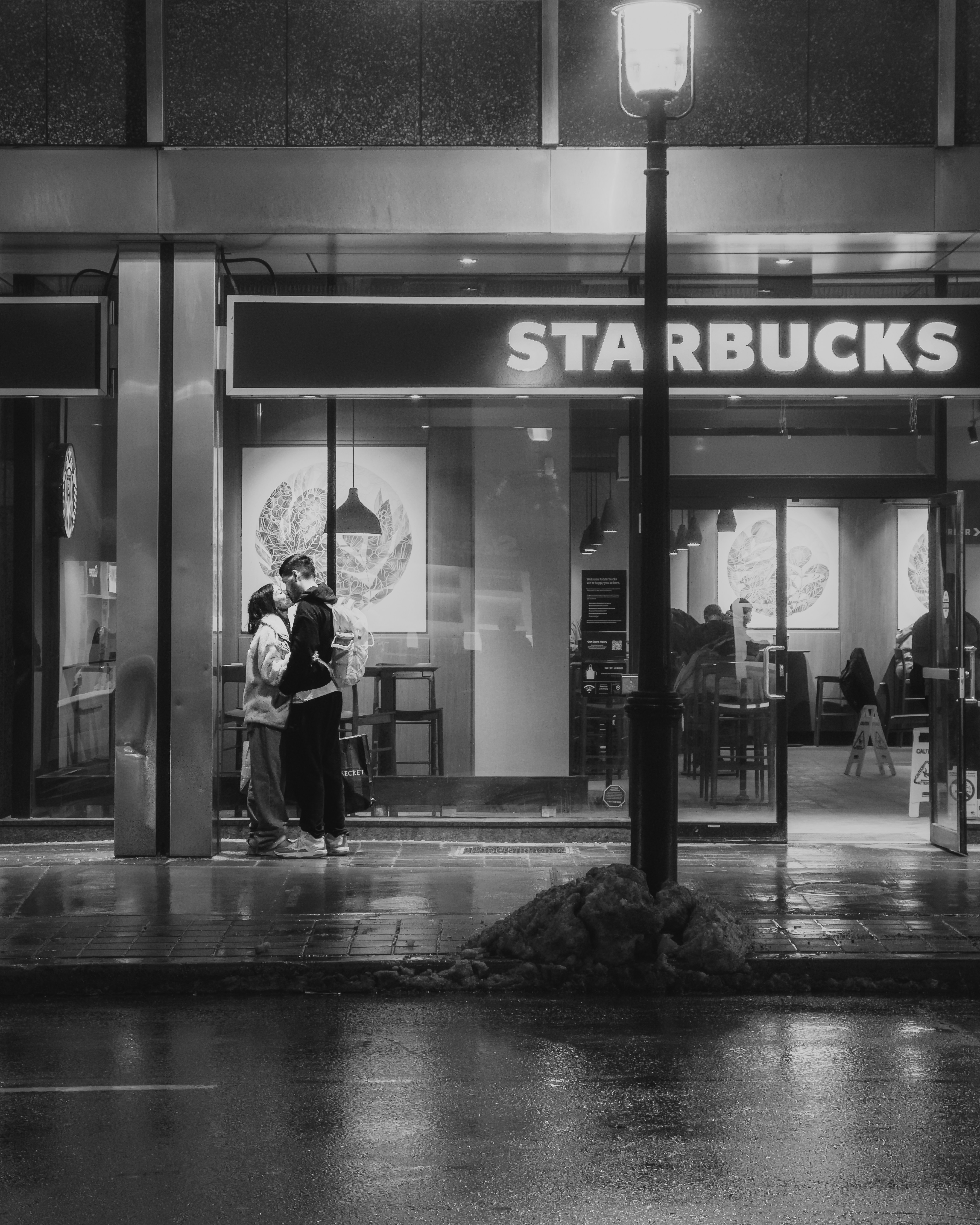 Couple kissing outside starbucks at night