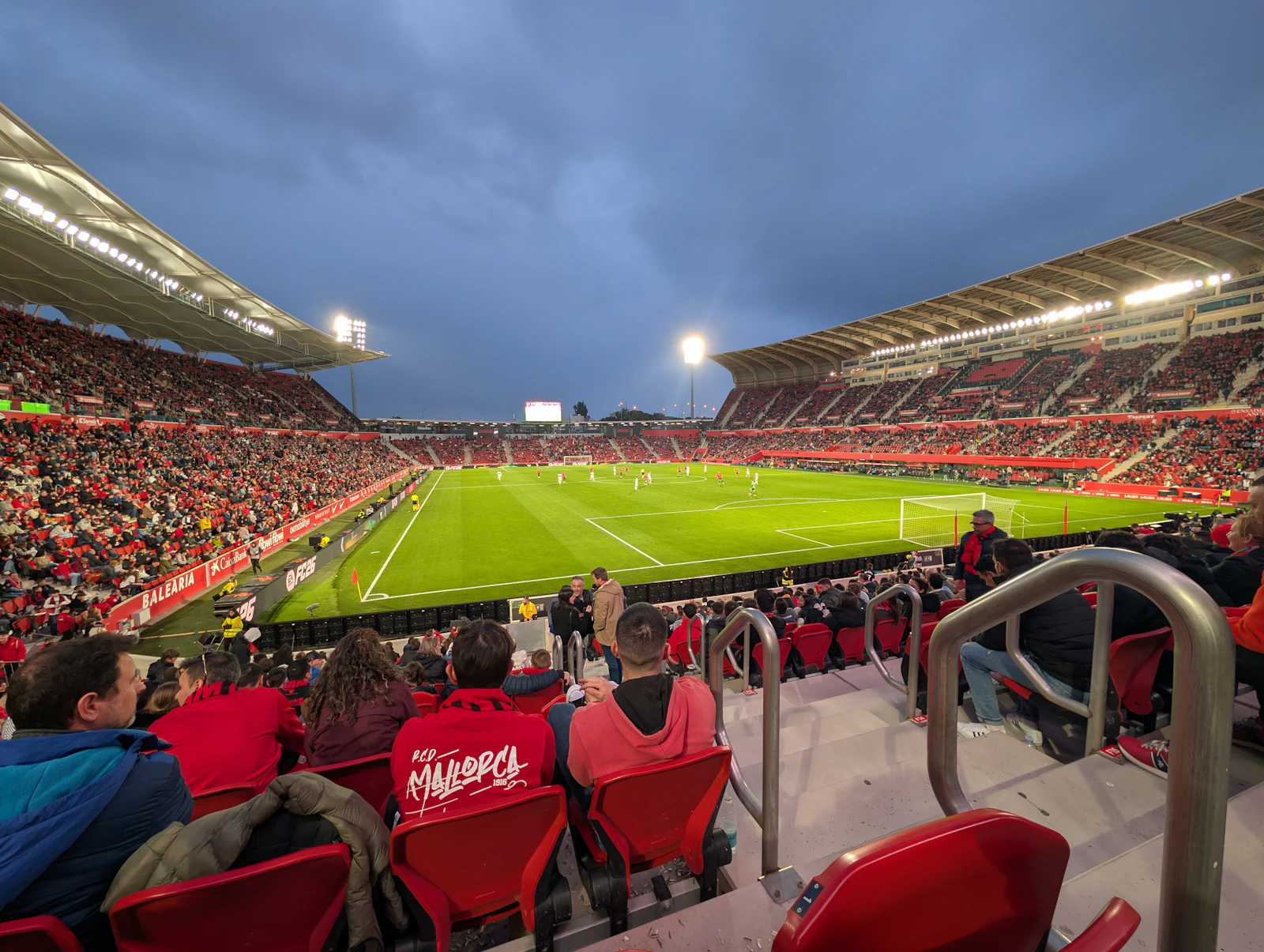 一座灯光明亮的足球场，球迷在看台上观看比赛