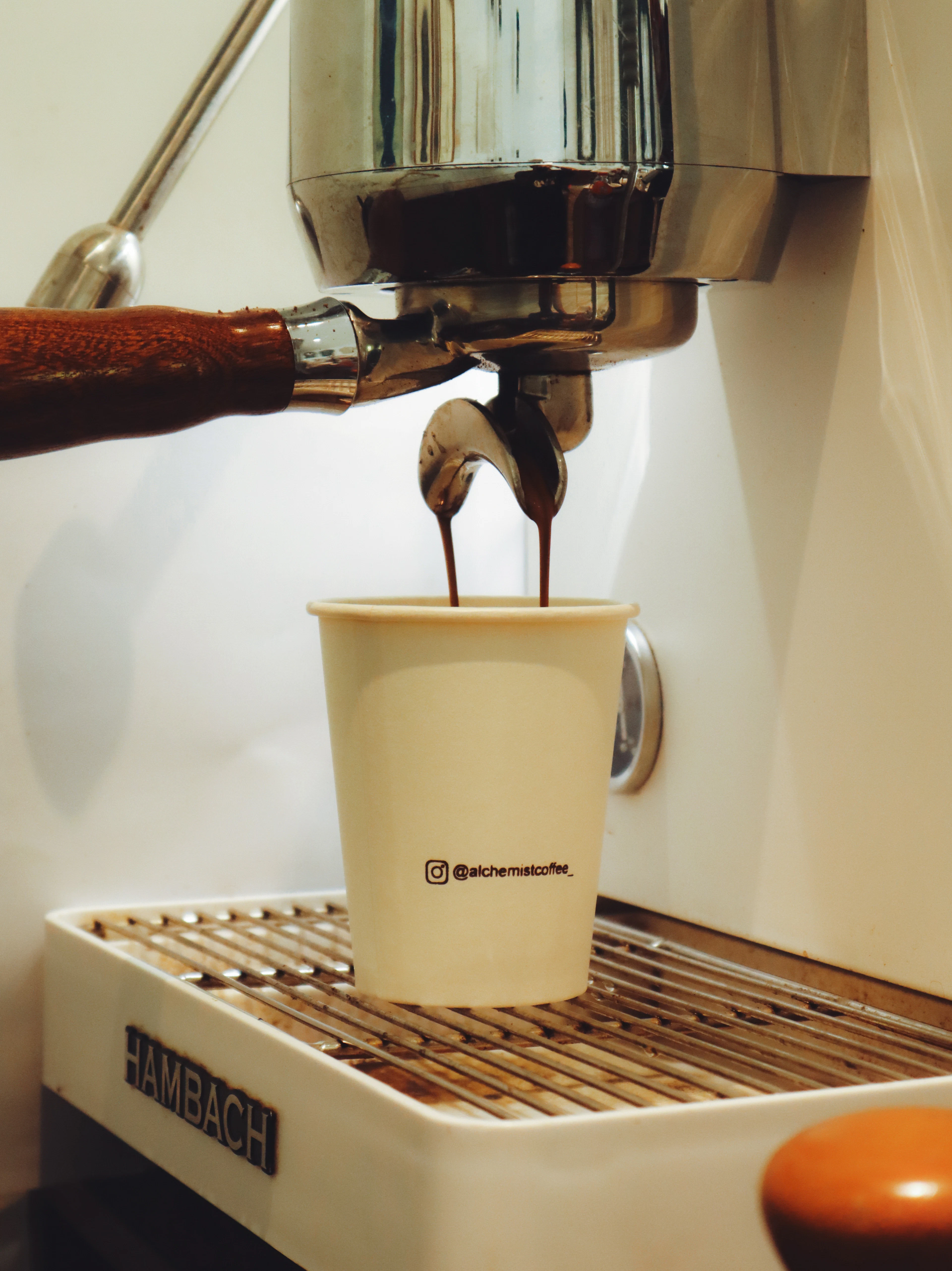 Espresso pouring from a machine into a paper takeaway cup