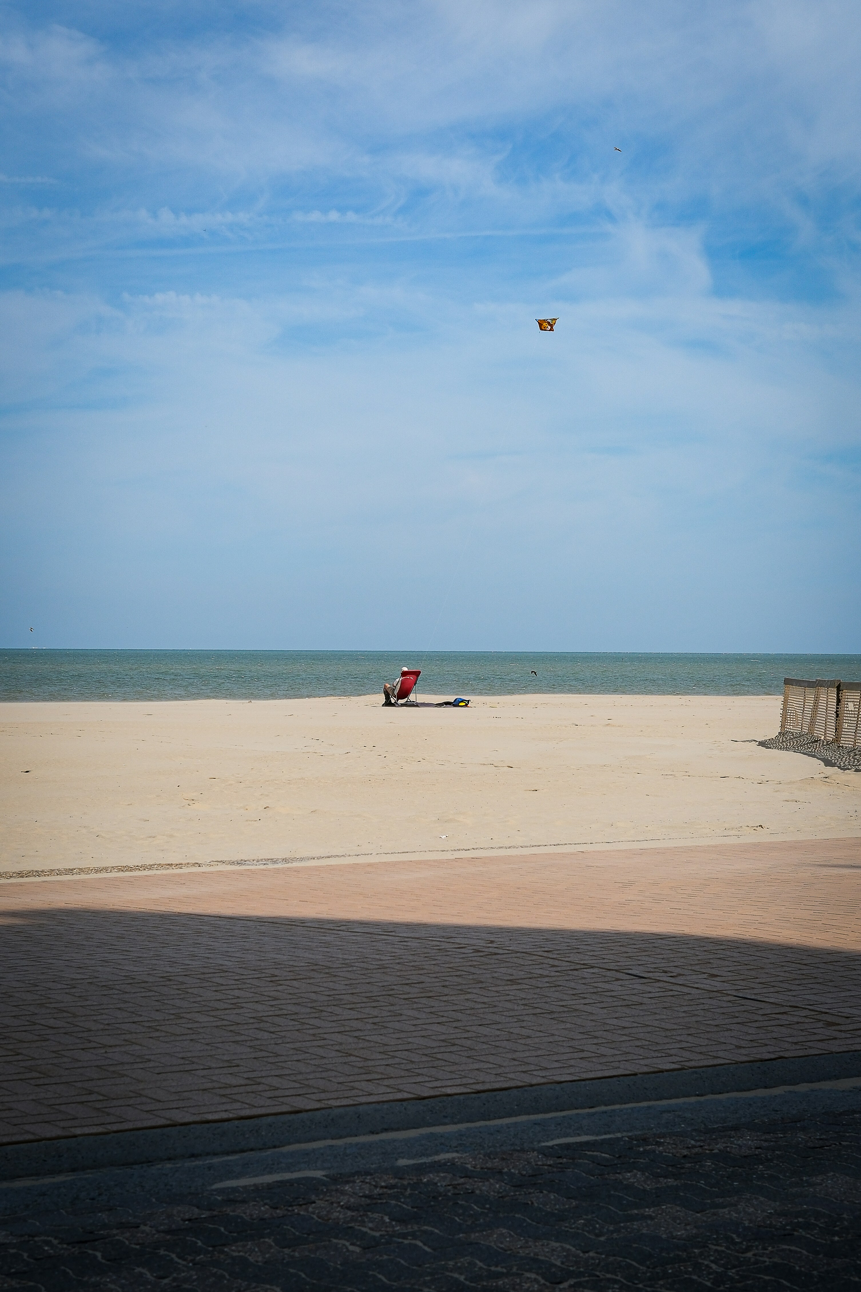 A lone red beach chair sits on a sandy beach.