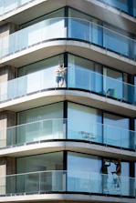 Man on balcony of modern building with glass railings