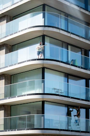Man on balcony of modern building with glass railings