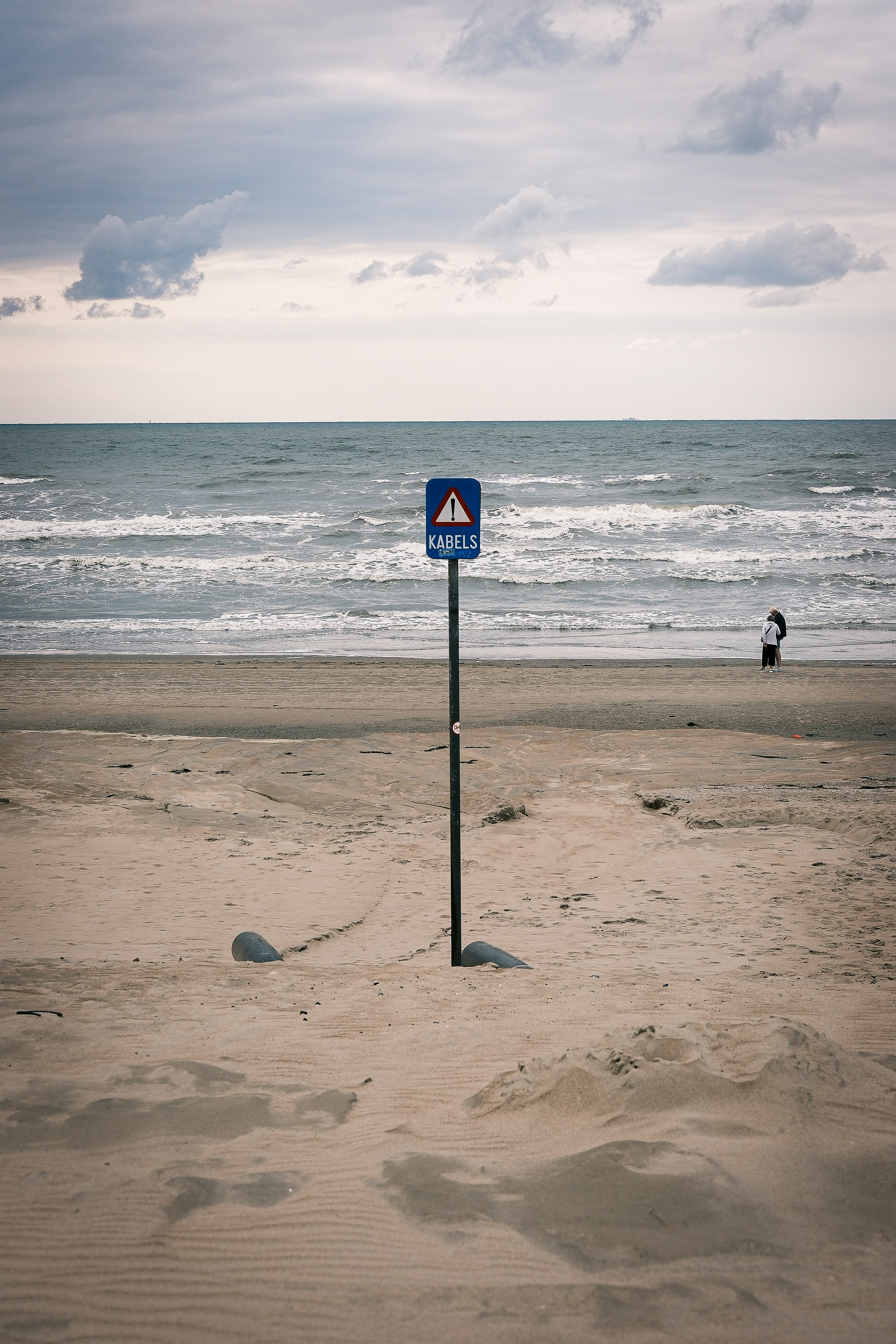 Warning sign on a sandy beach with ocean background