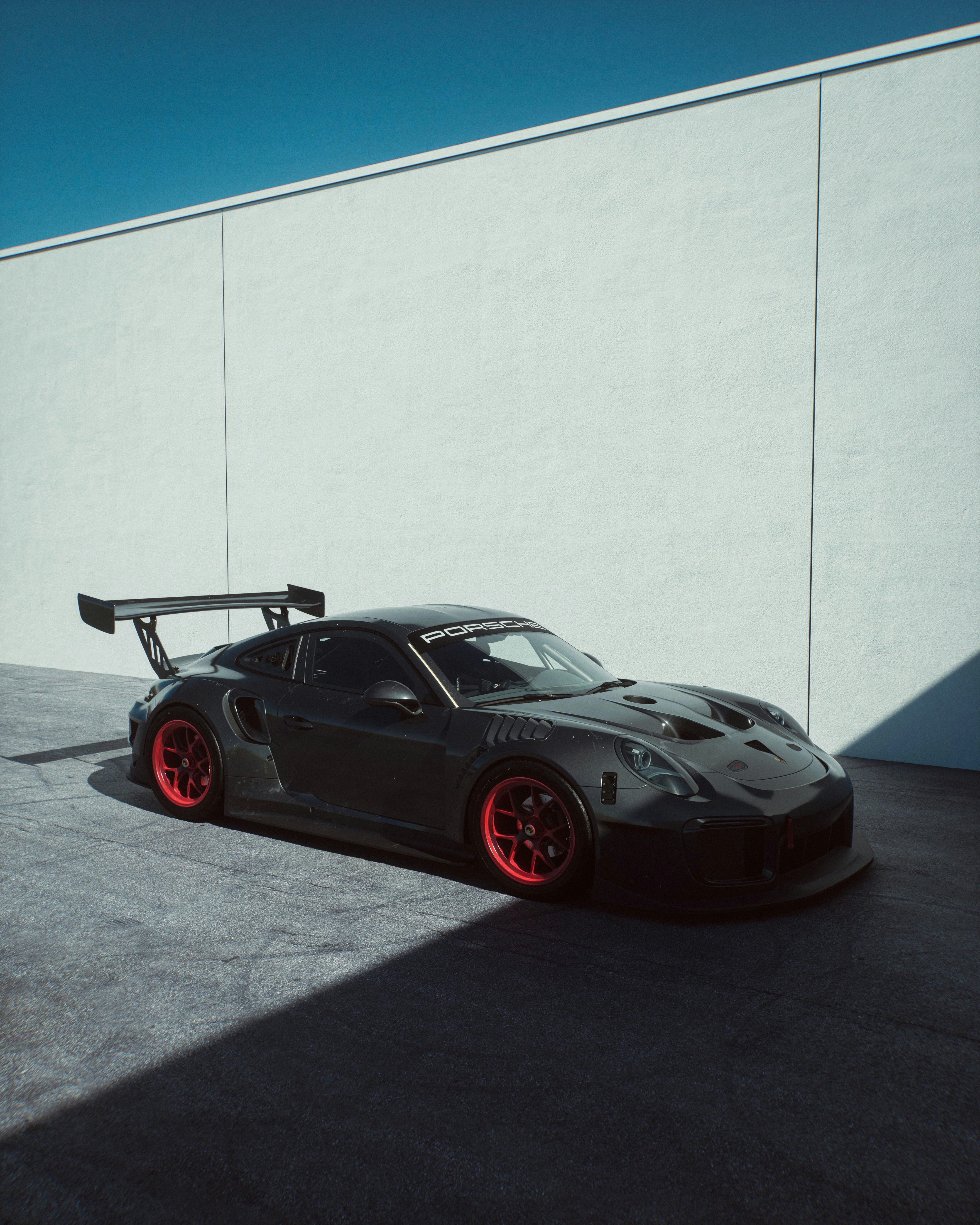 Um carro esportivo cinza escuro com rodas vermelhas.