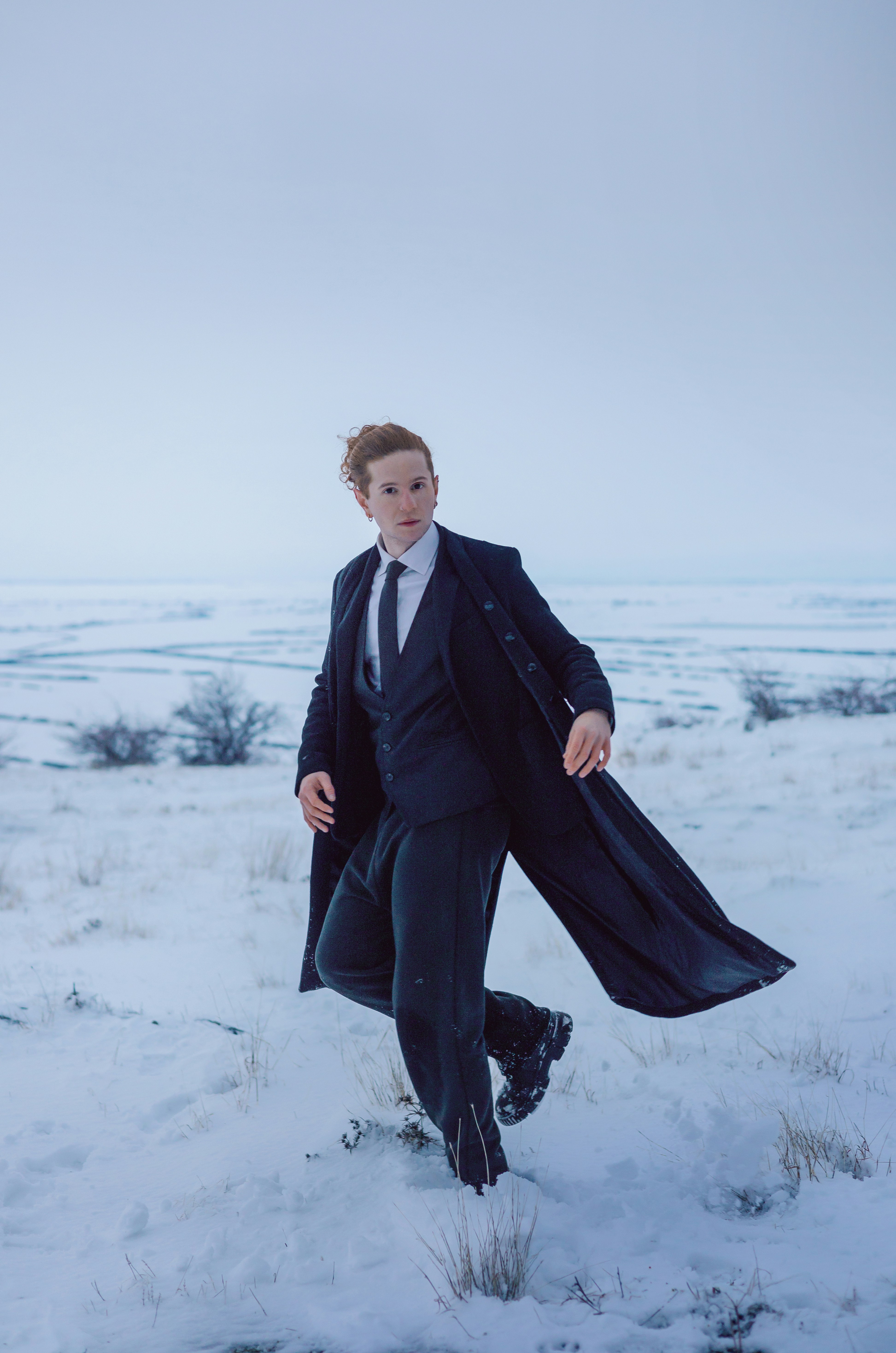 Homem de terno caminhando por uma paisagem nevada.