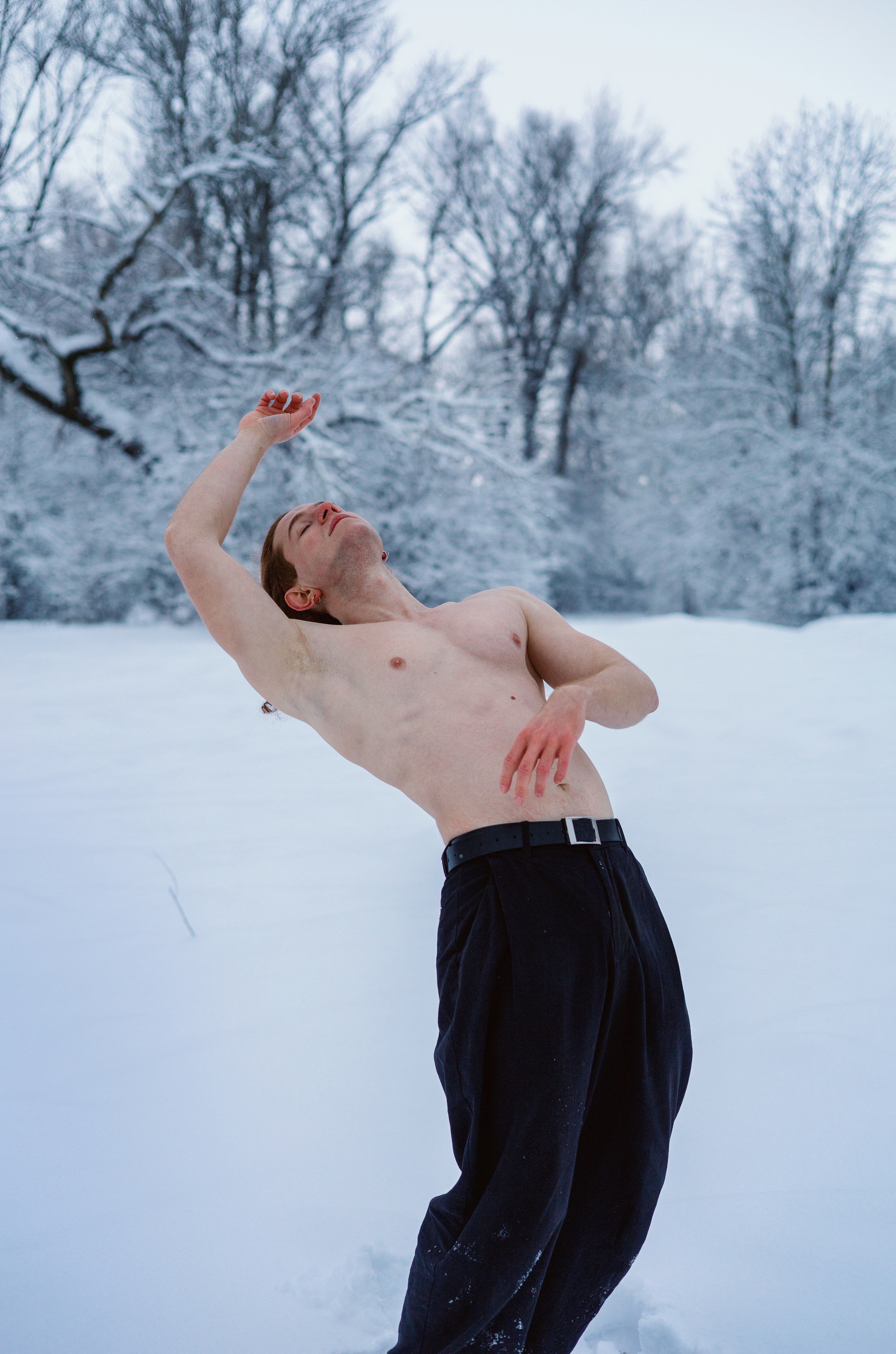 Homem sem camisa dançando em floresta nevada