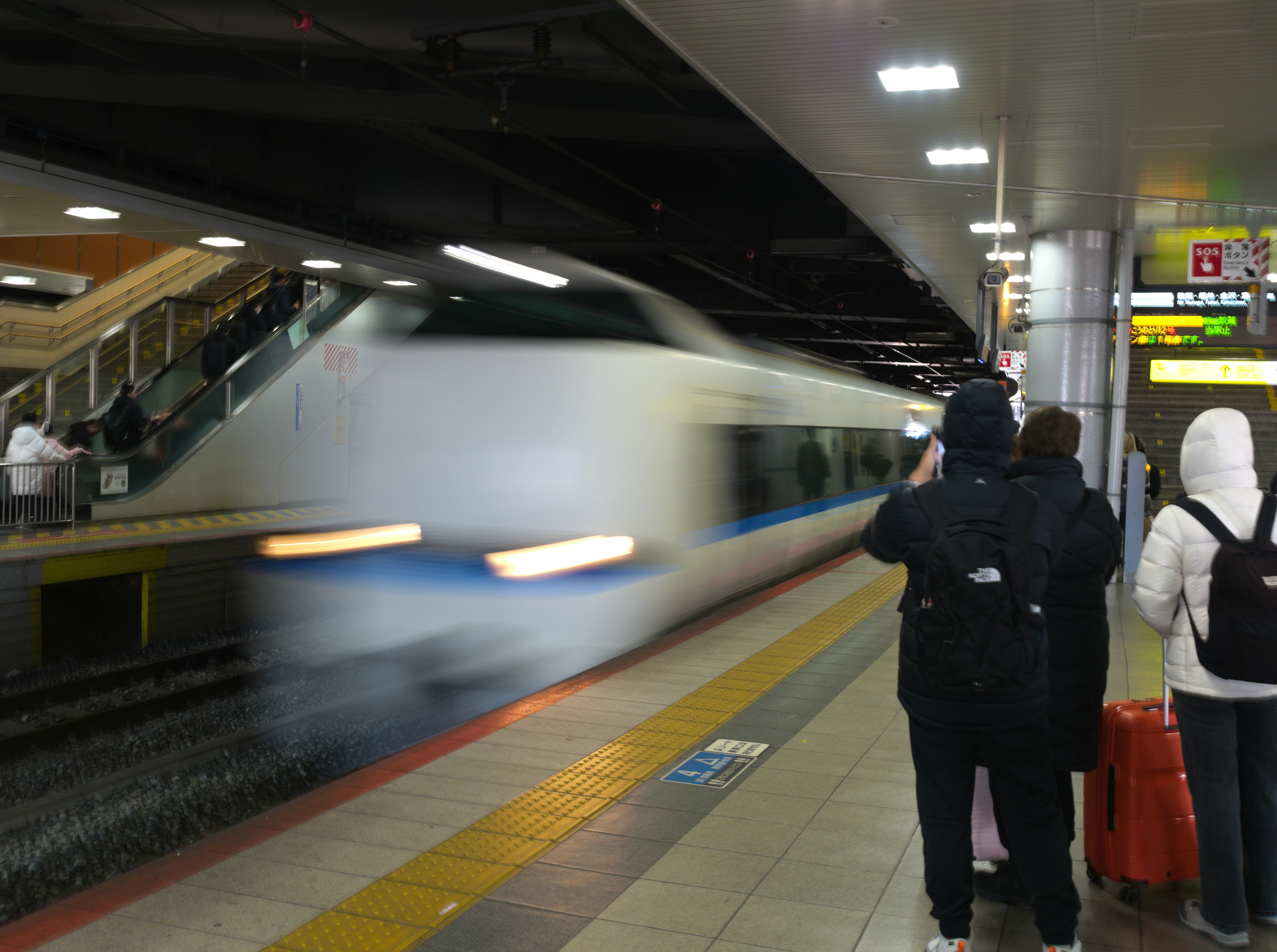 A train arriving at a station with people waiting