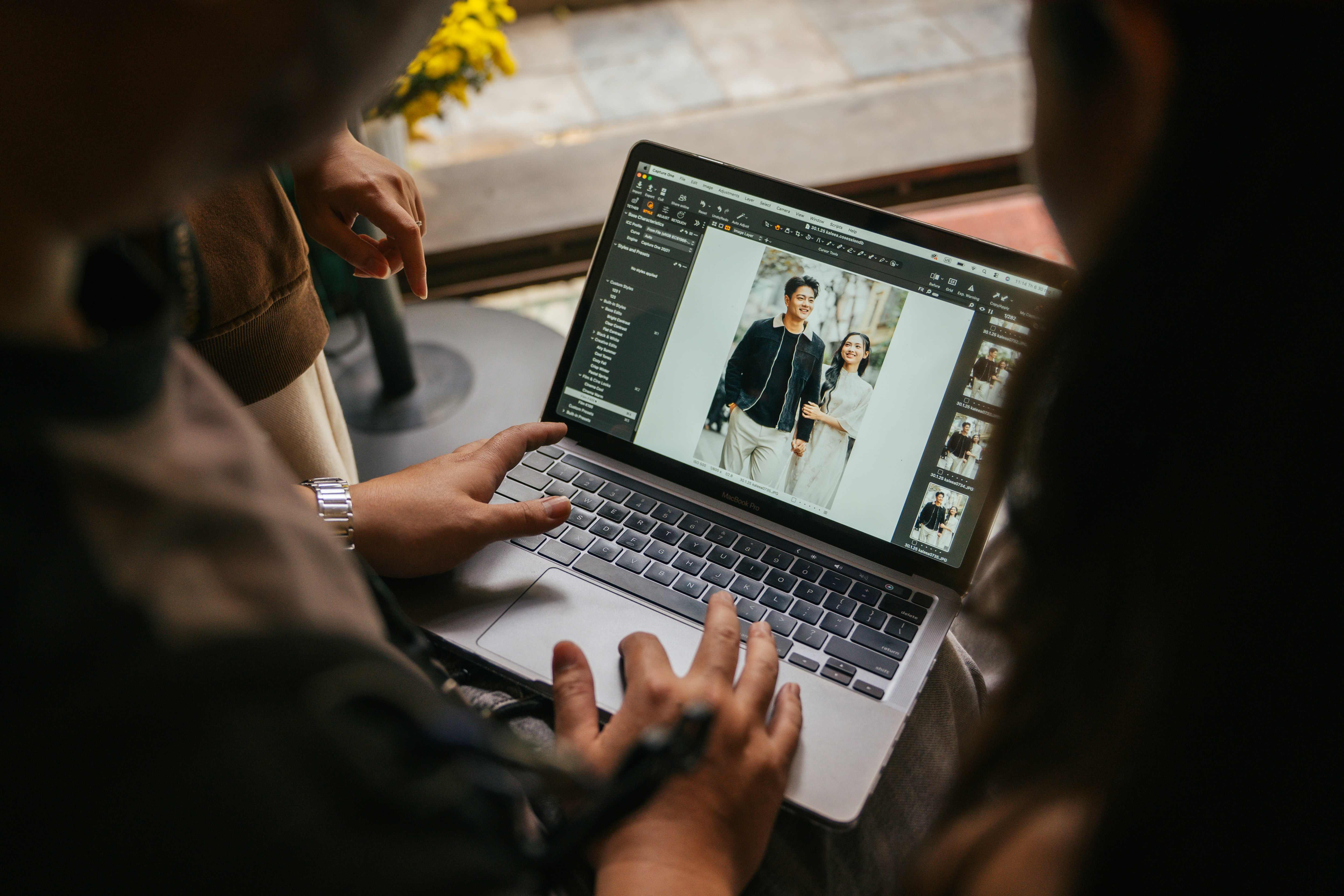 Two people looking at a laptop screen displaying photos