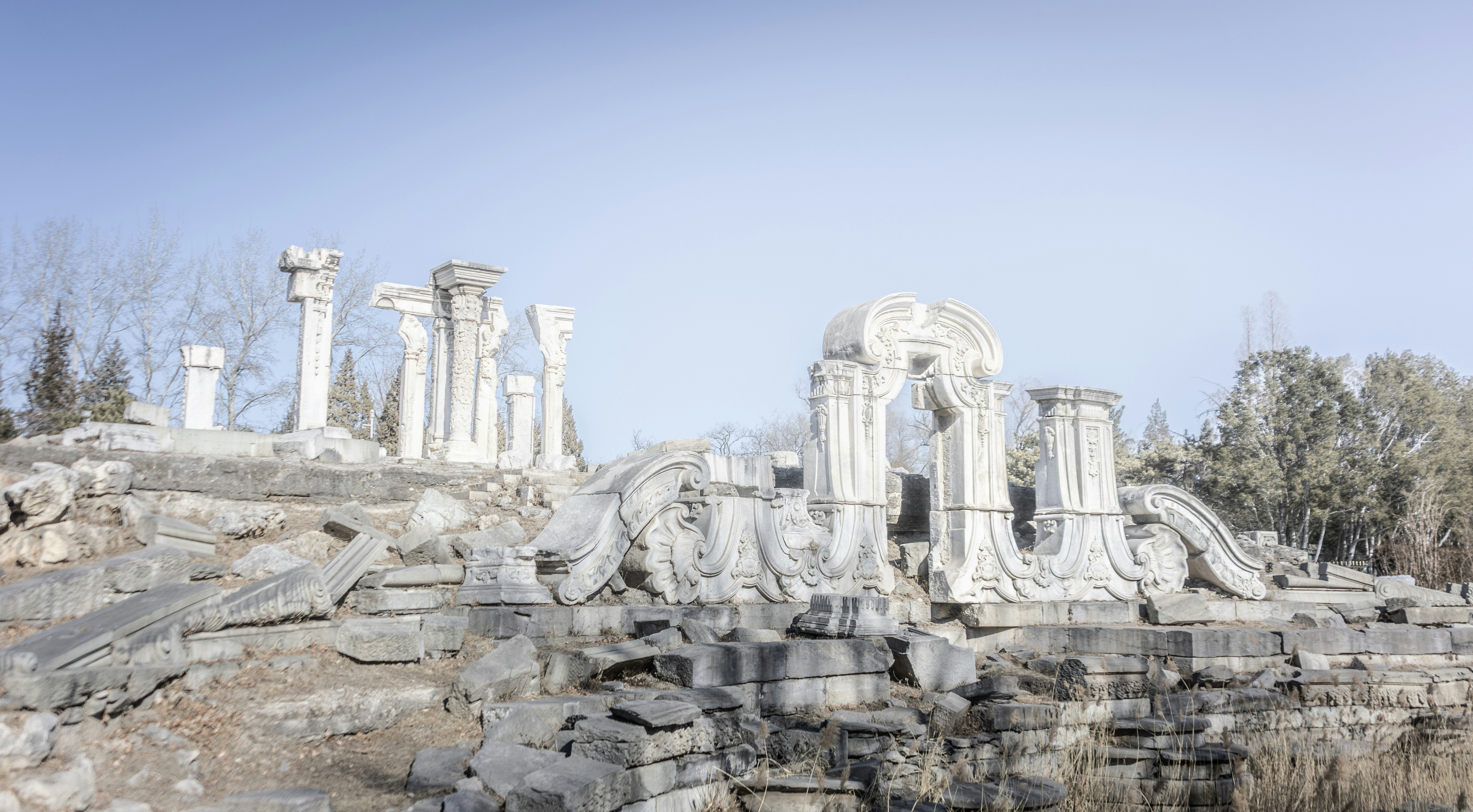 Ancient stone ruins with classical architectural elements and trees.