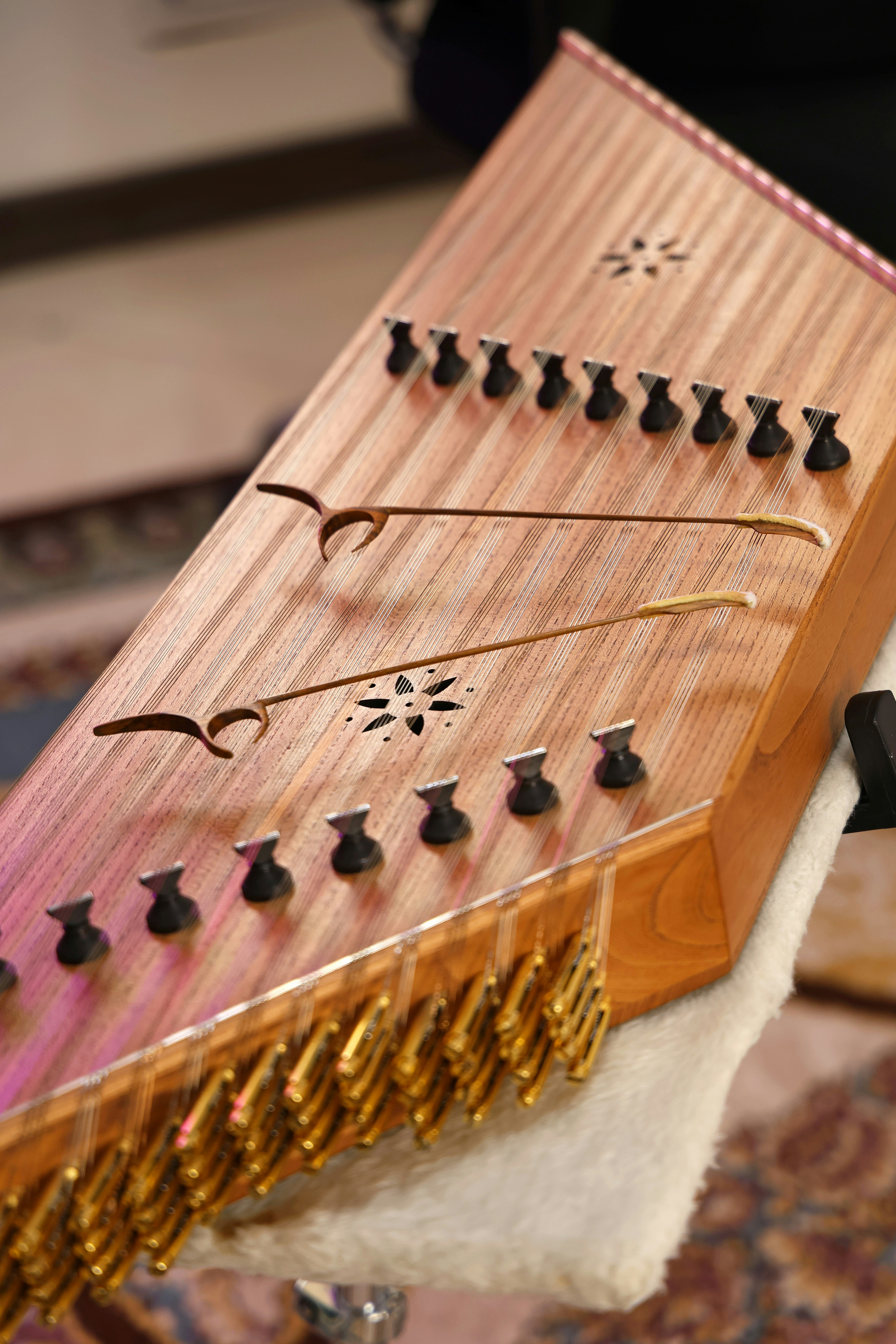 A close-up of a wooden dulcimer with gold strings.