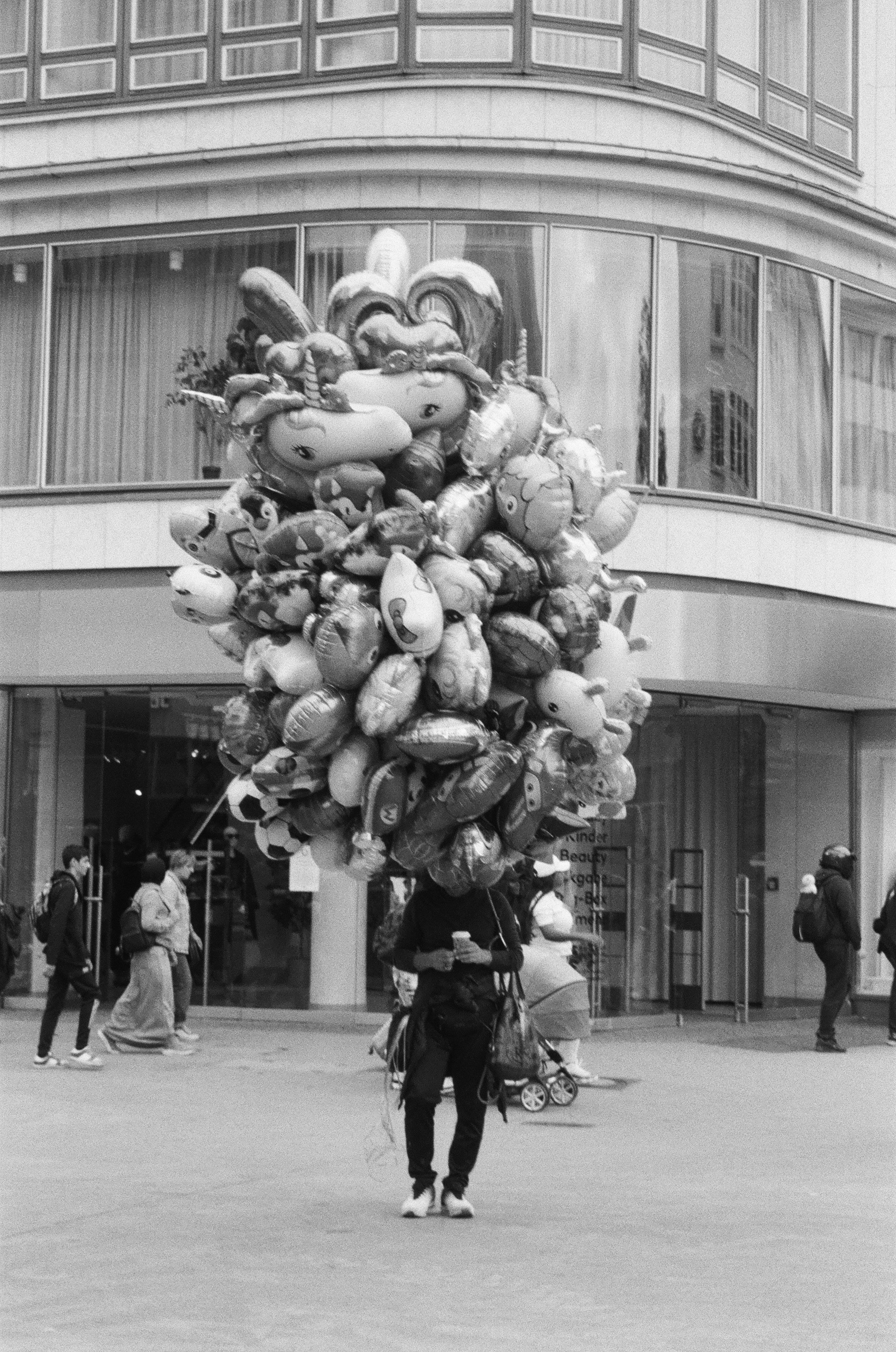 Person carrying a large bunch of balloons outside balloons