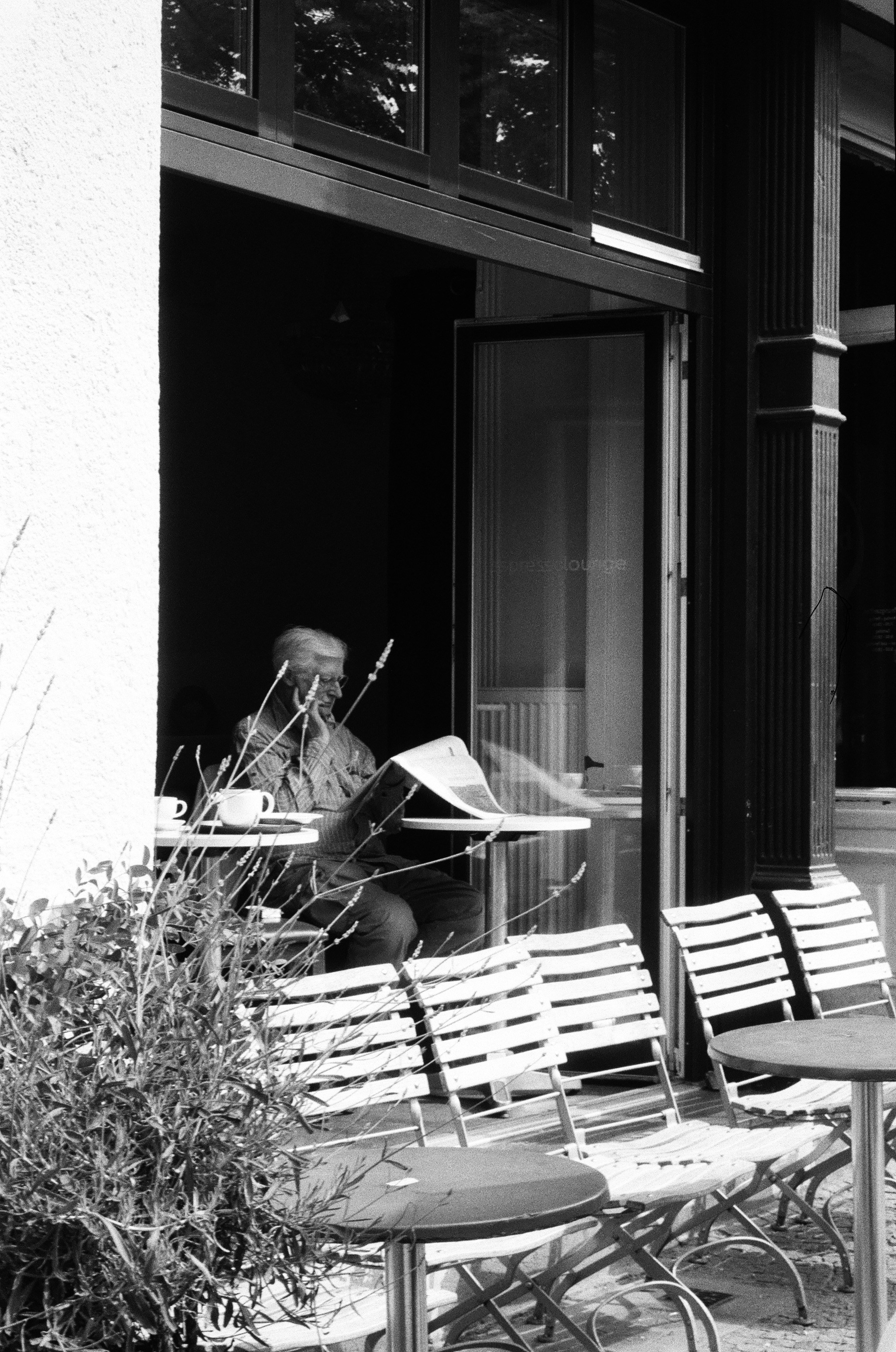 Man reading newspaper at outdoor cafe table