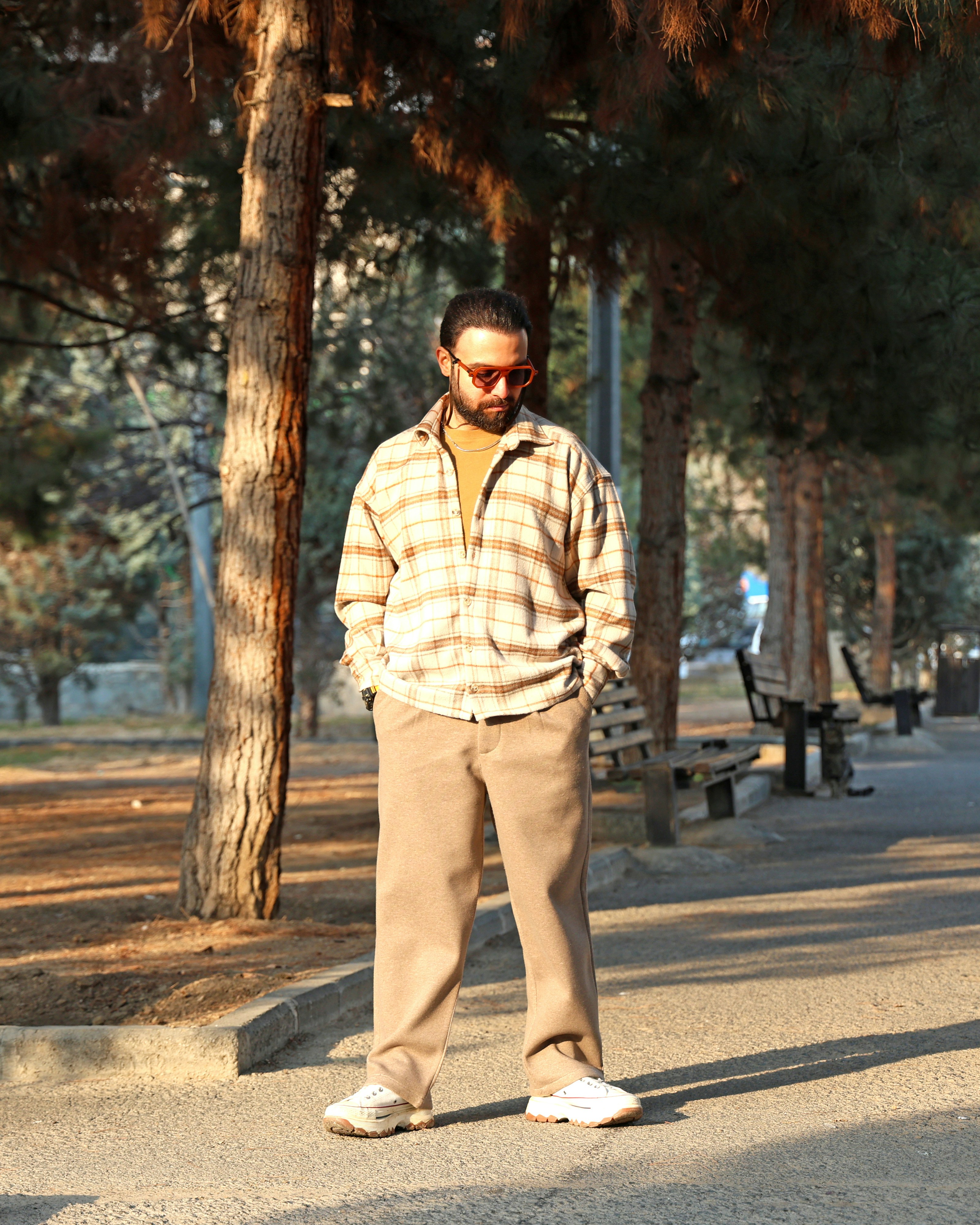 Man in plaid shirt standing in a park.