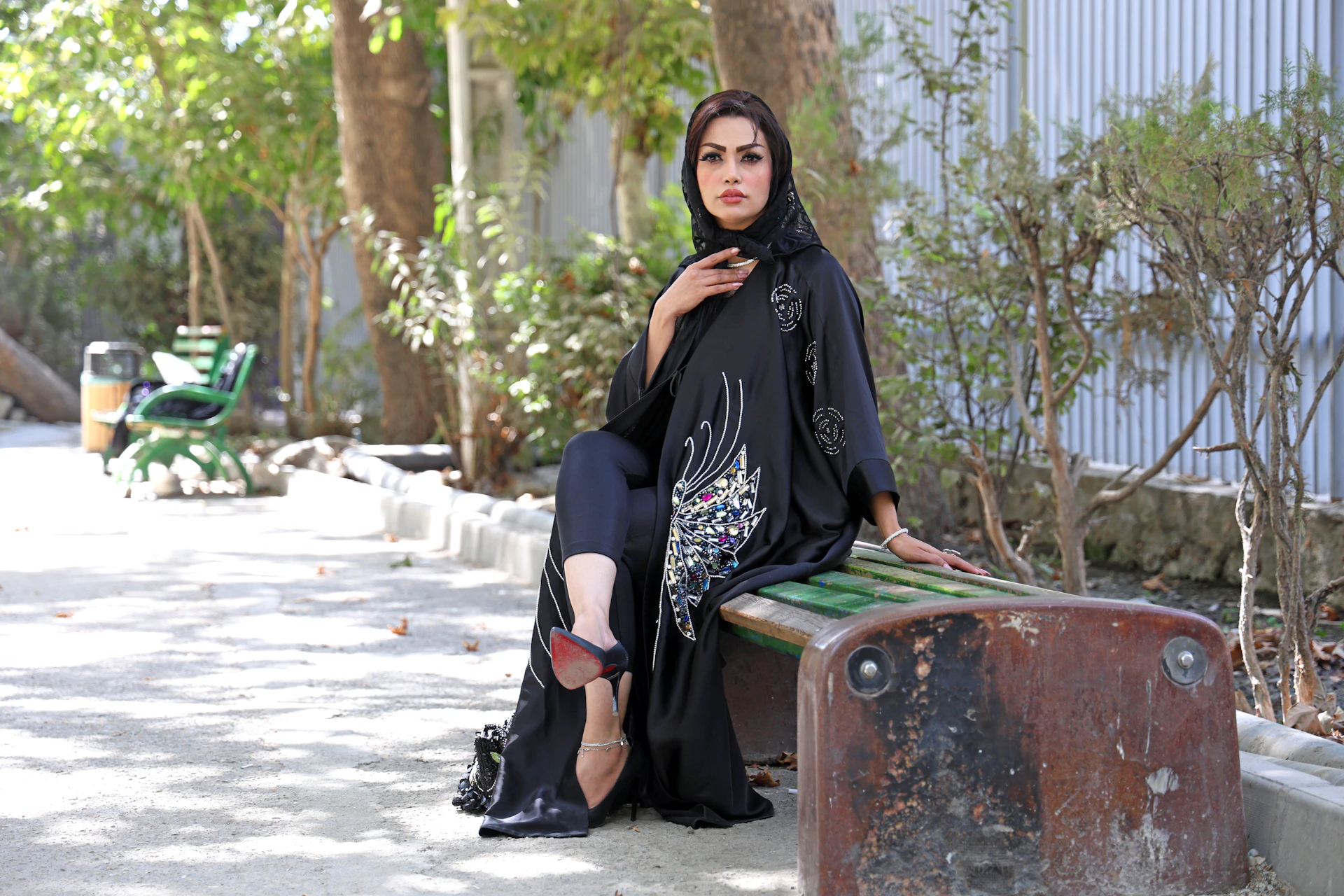 Woman in black abaya sitting on a park bench.