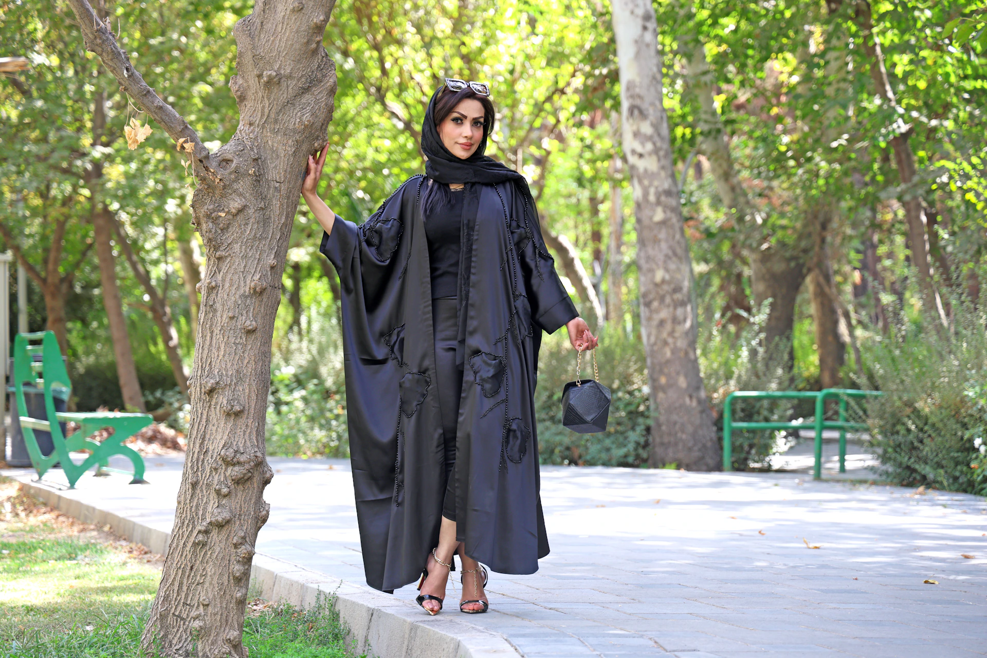 Woman in black abaya posing outdoors near trees