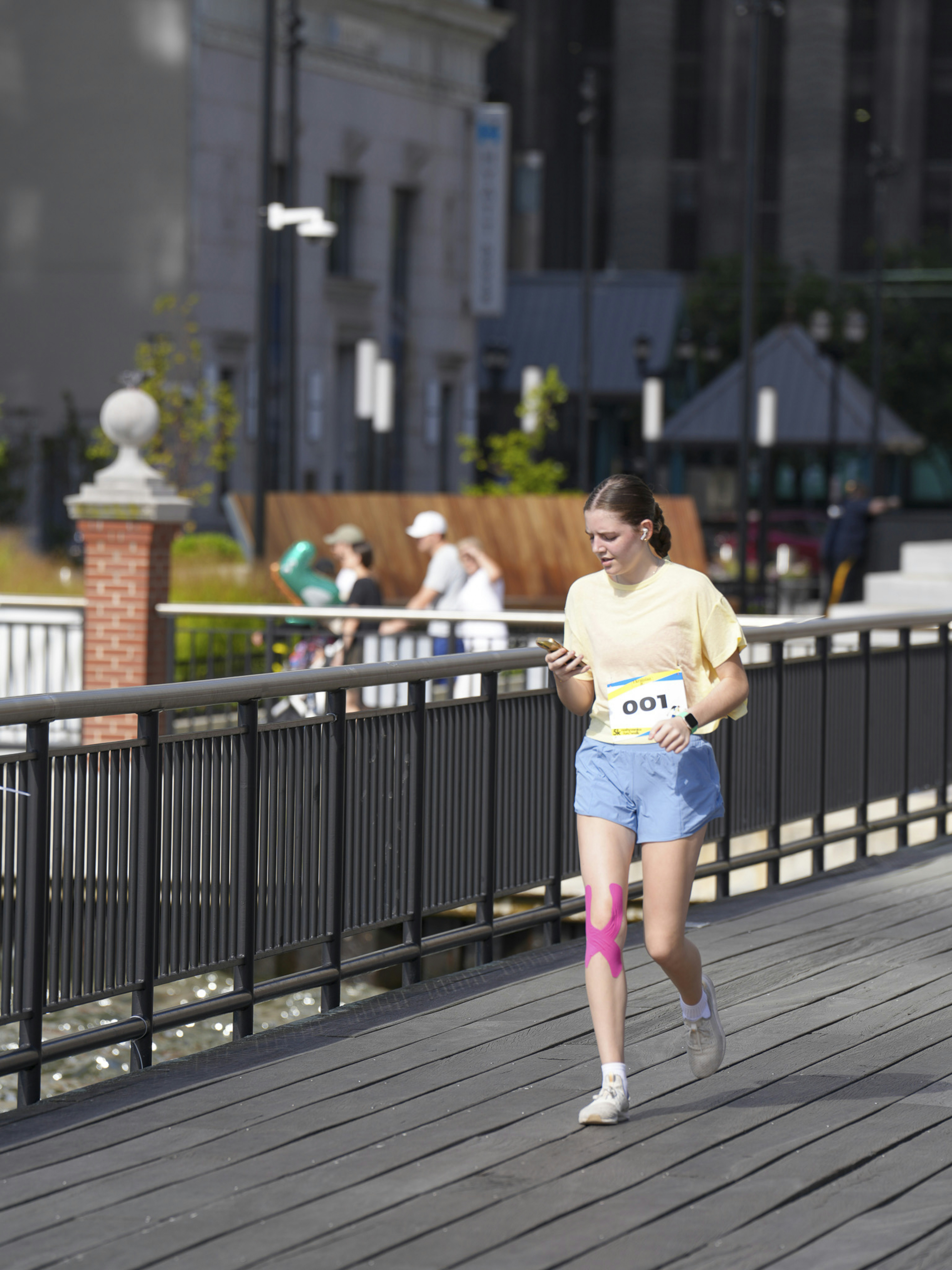 Young woman running on a wooden boardwalk with buildings behind.
