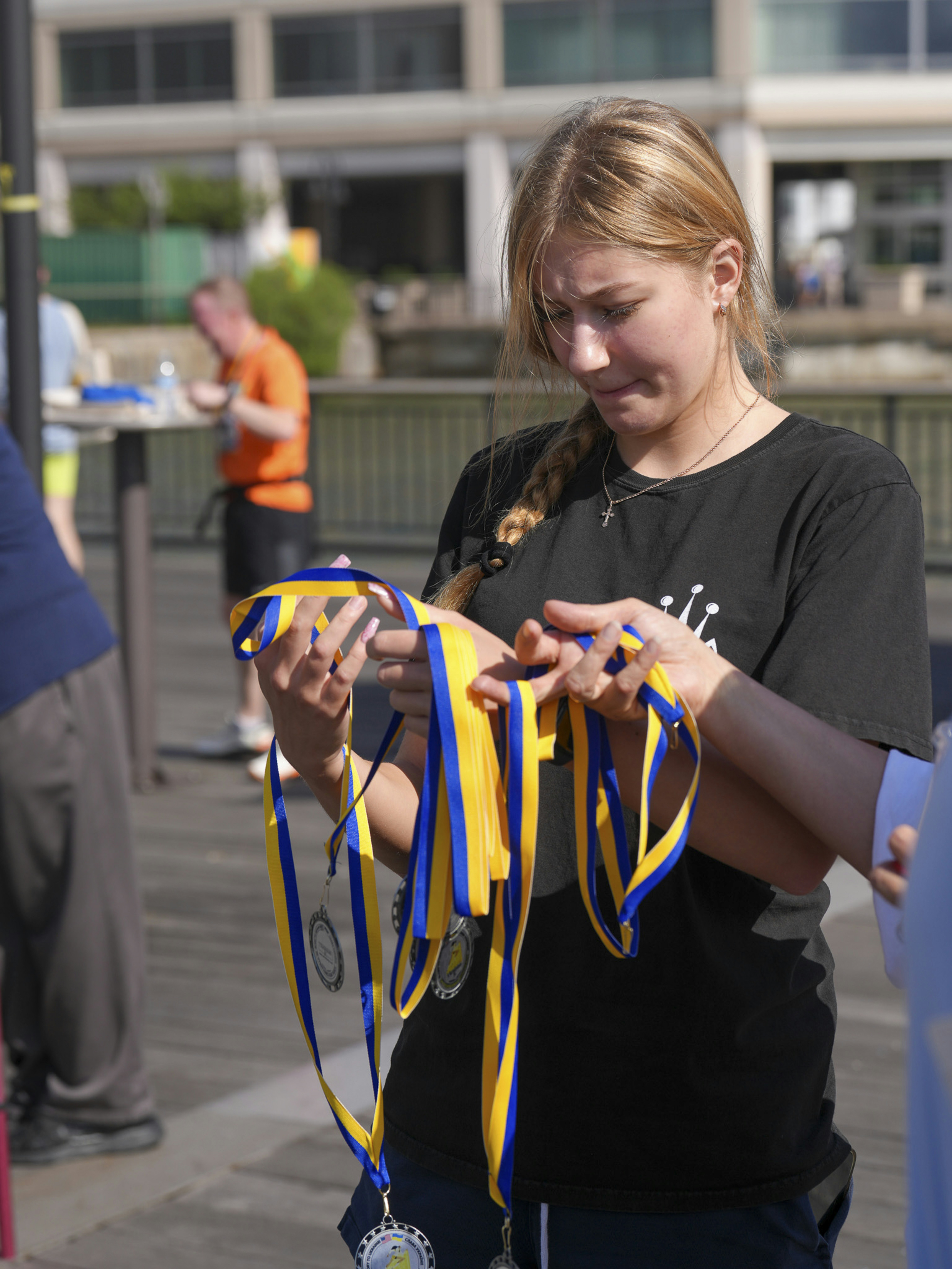 Young woman holding blue and yellow ribbons with medals