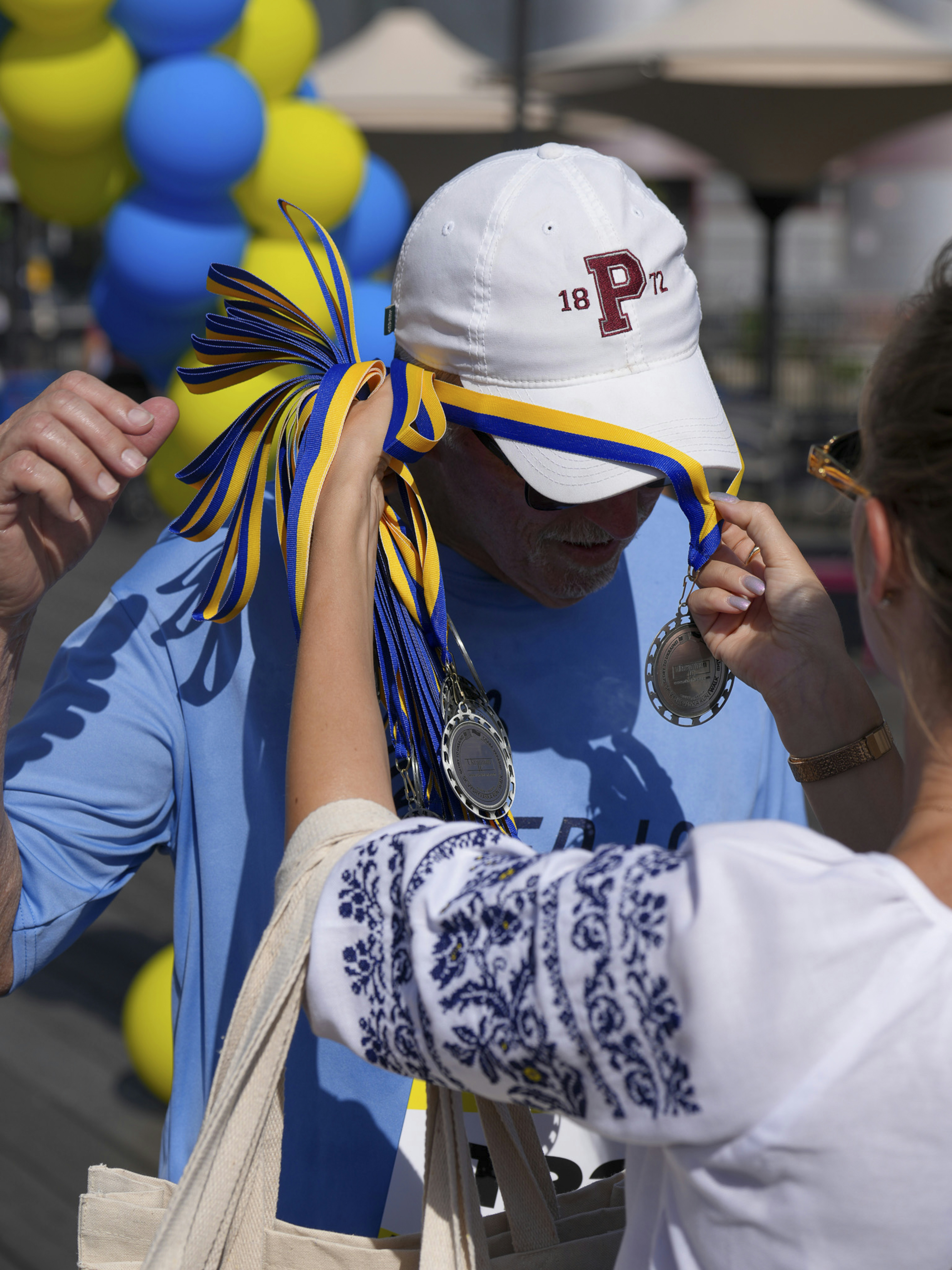 Man receives medals with blue and yellow ribbons
