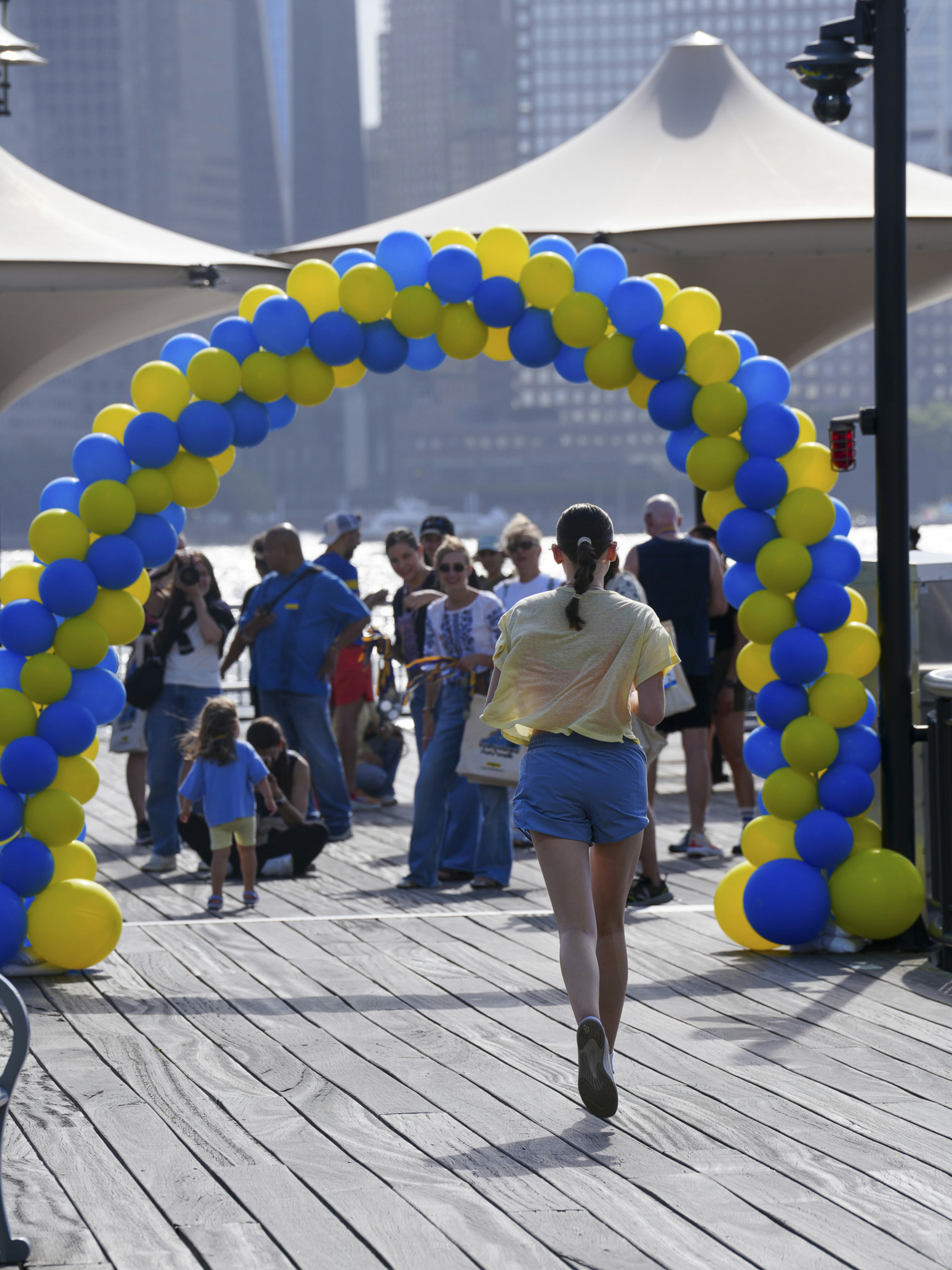 People walk under a blue and yellow balloon arch. photo – Free Crowd ...