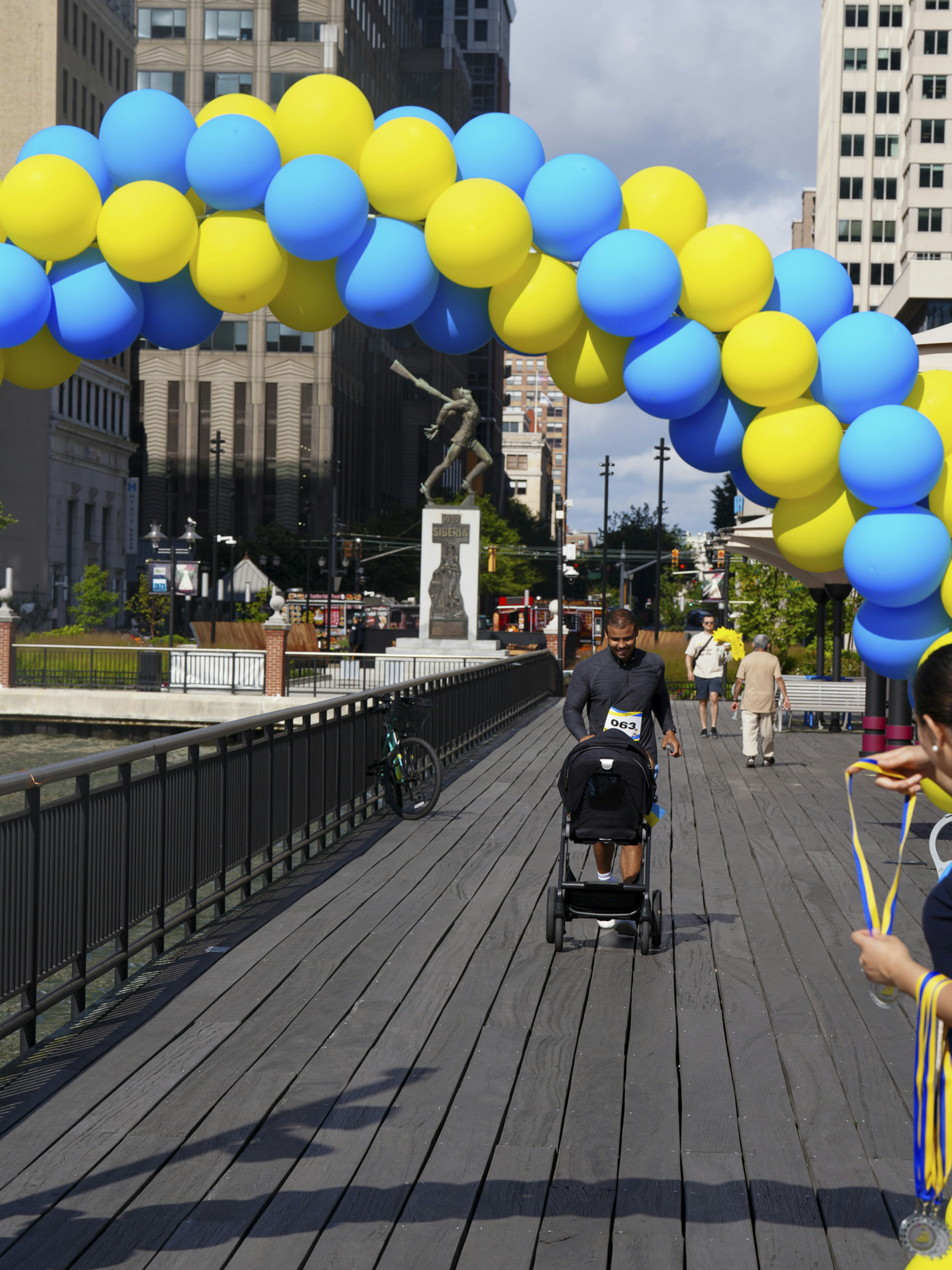 Die Leute gehen unter einem blau-gelben Ballonbogen hindurch.