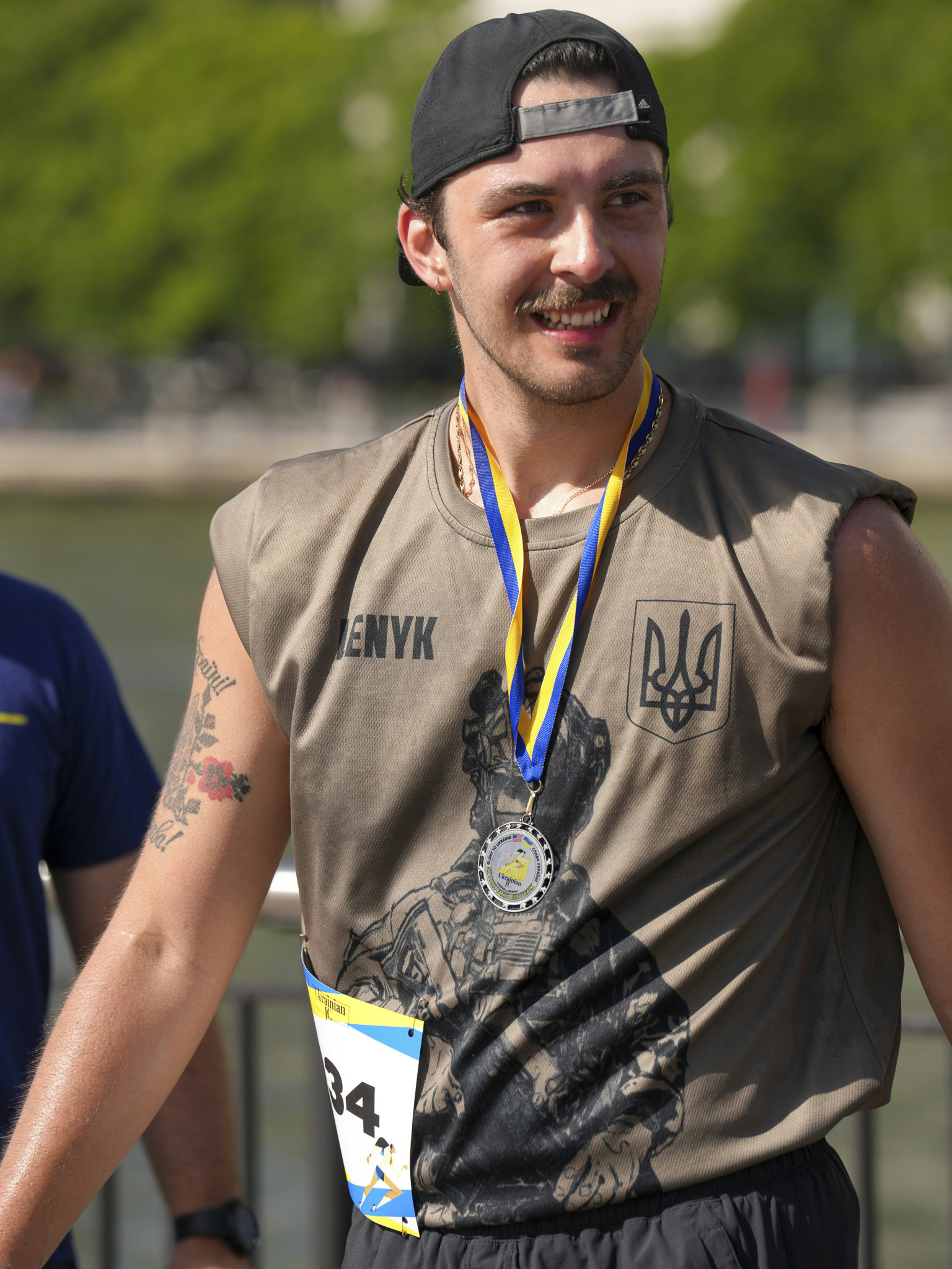 Ein Mann mit Medaille und Laufstartnummer lächelt