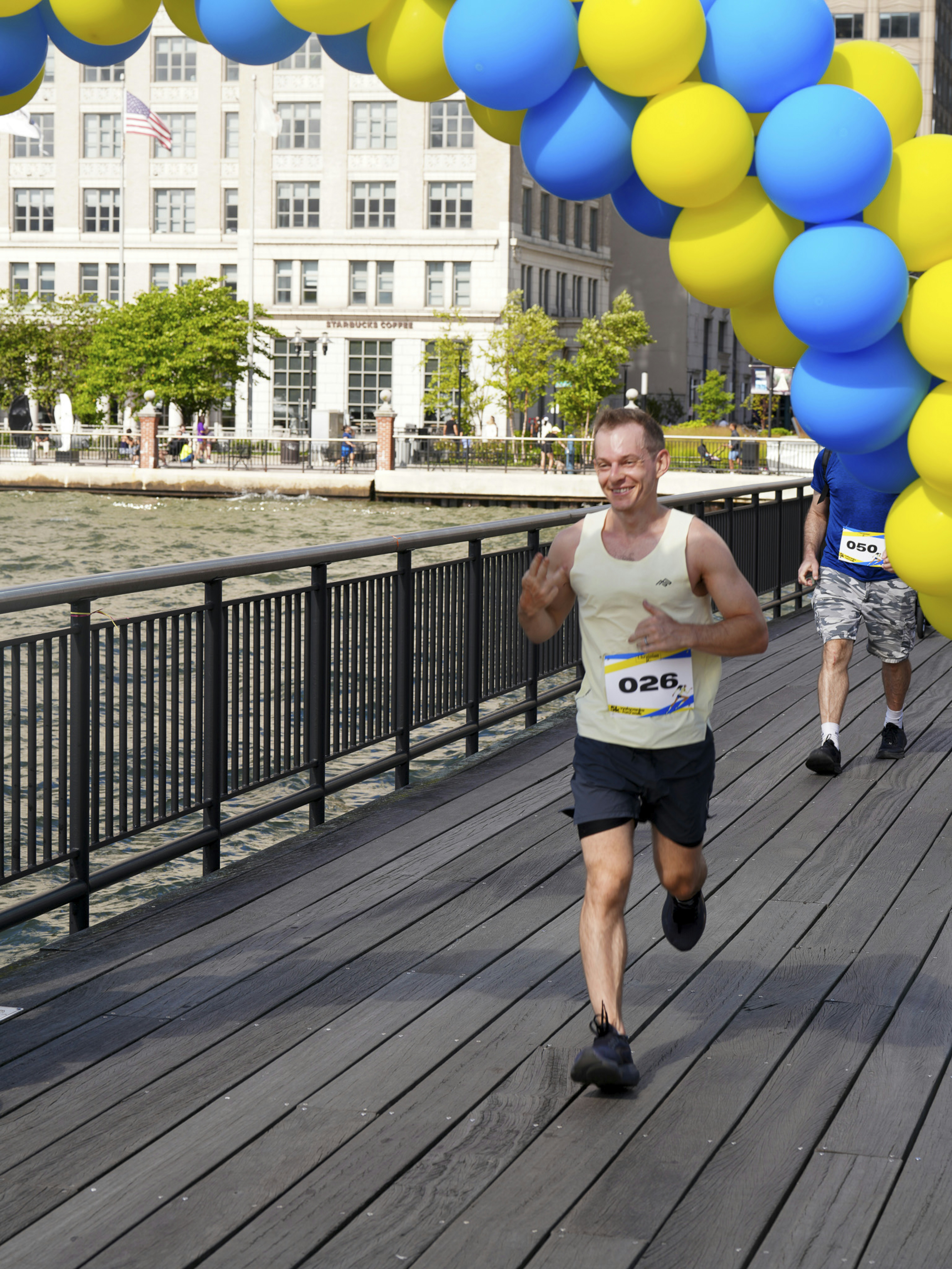 Der Mann läuft unter dem blau-gelben Ballonbogen hindurch.