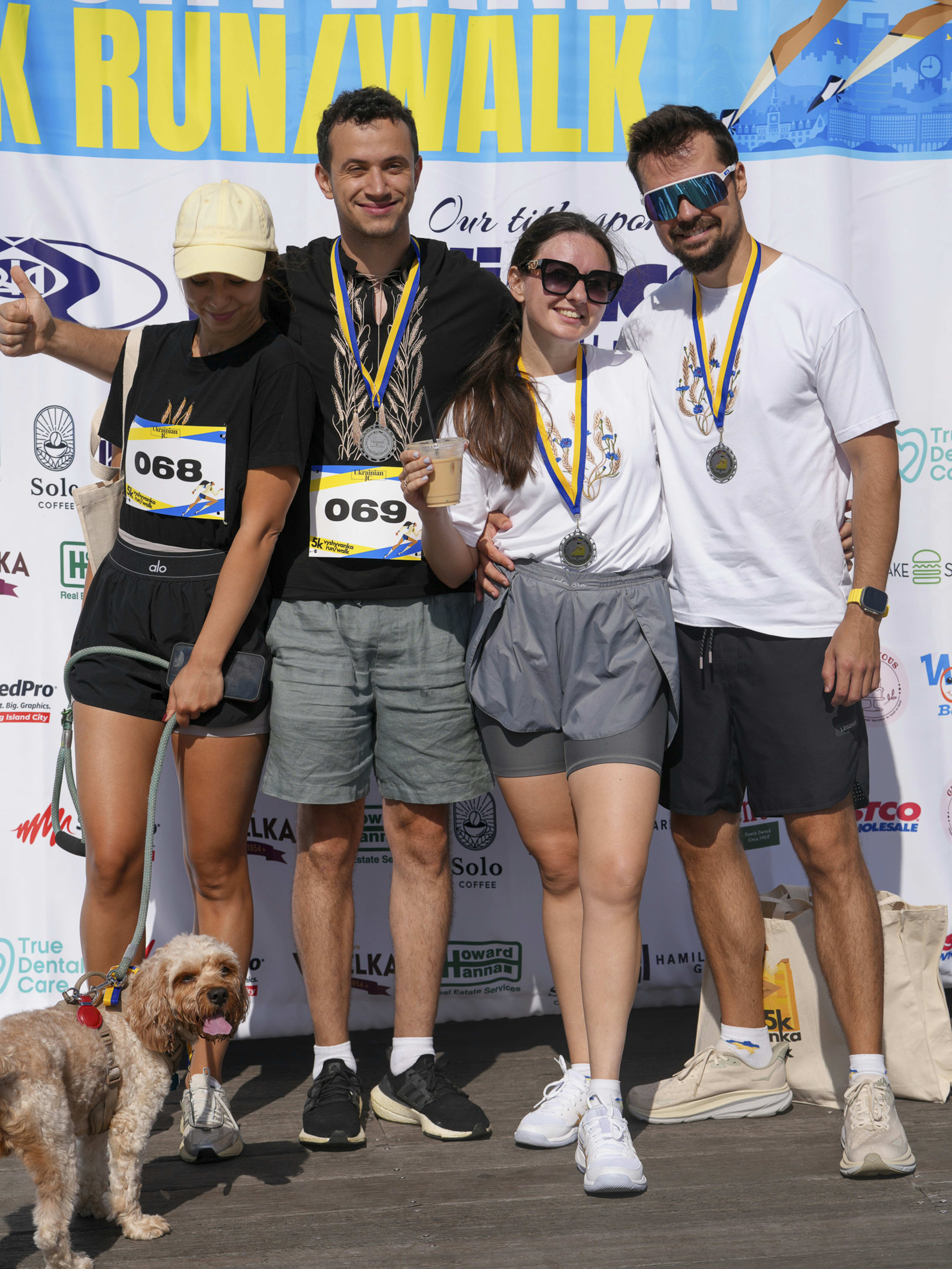 Four smiling people and a dog at an event