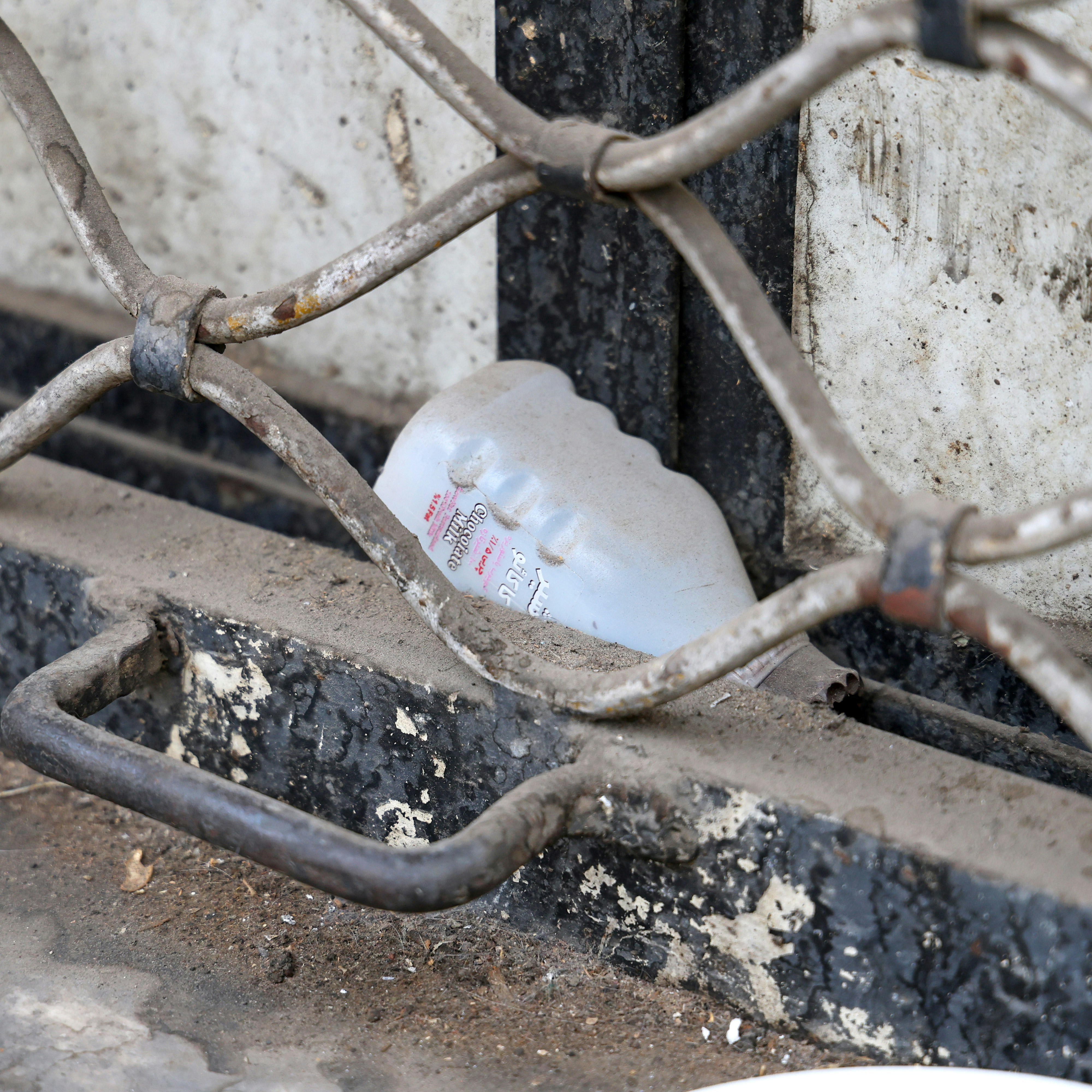 Plastic bottle behind a metal grate