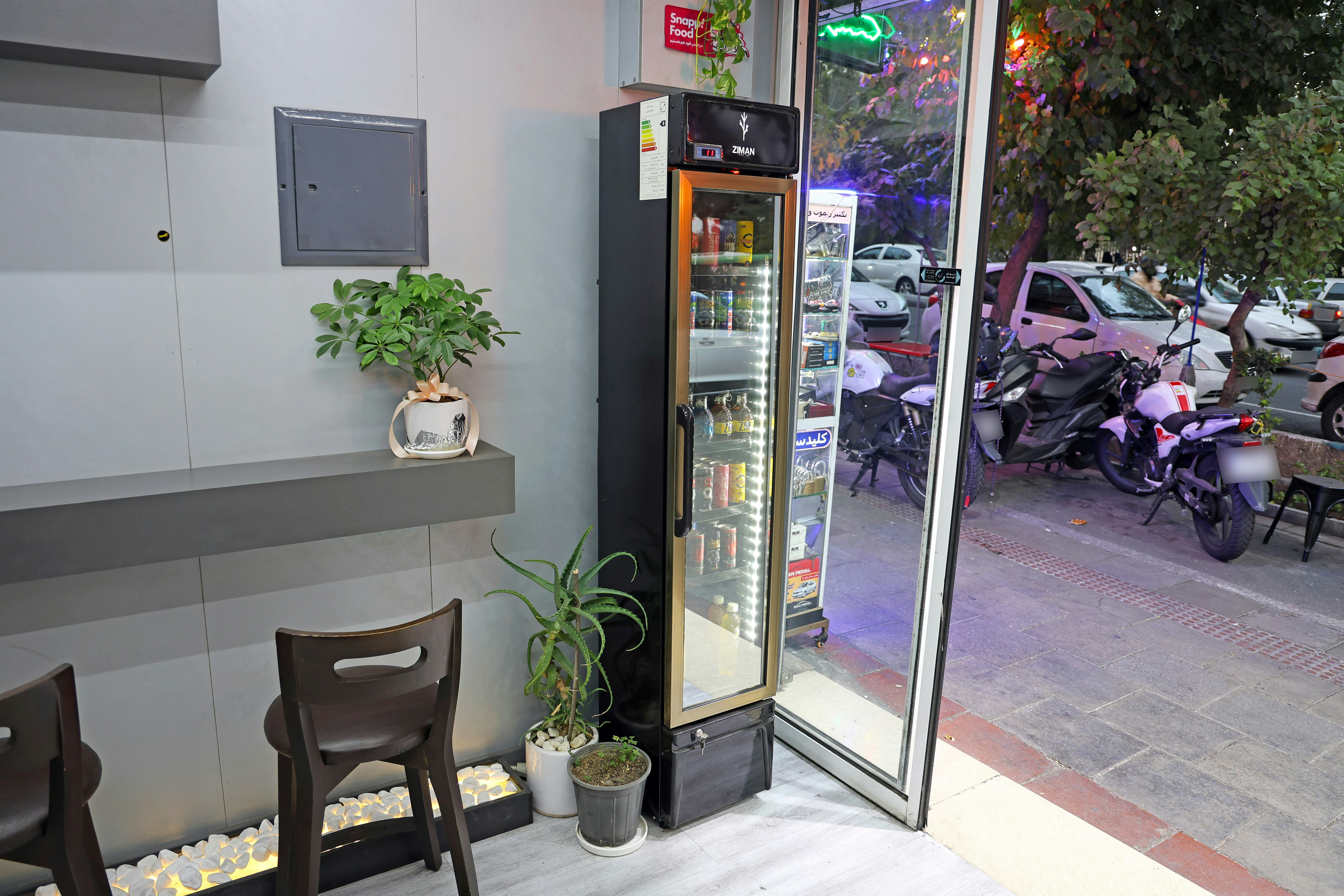 A refrigerator filled with drinks next to a window.