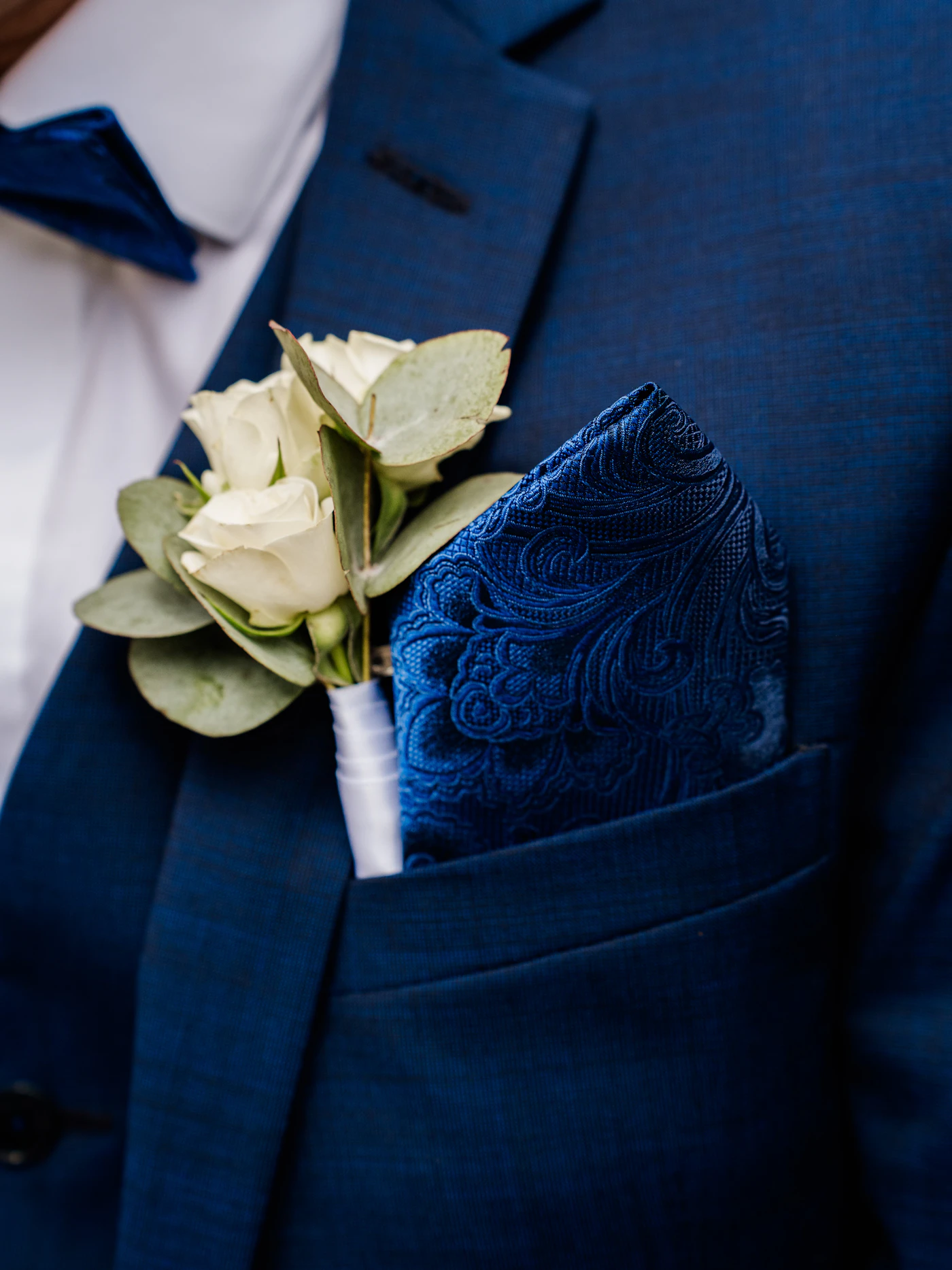 How to make your own boutonnieres — A close-up of a groom's lapel with a freshly pinned DIY boutonniere.
