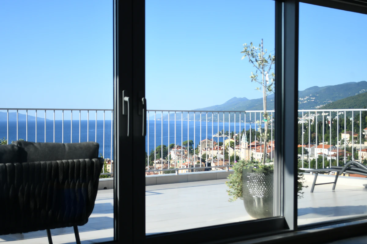 Sacada moderna com porta e guarda-corpo de vidro e vista para o mar