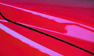 Close-up of a shiny red car surface with reflections