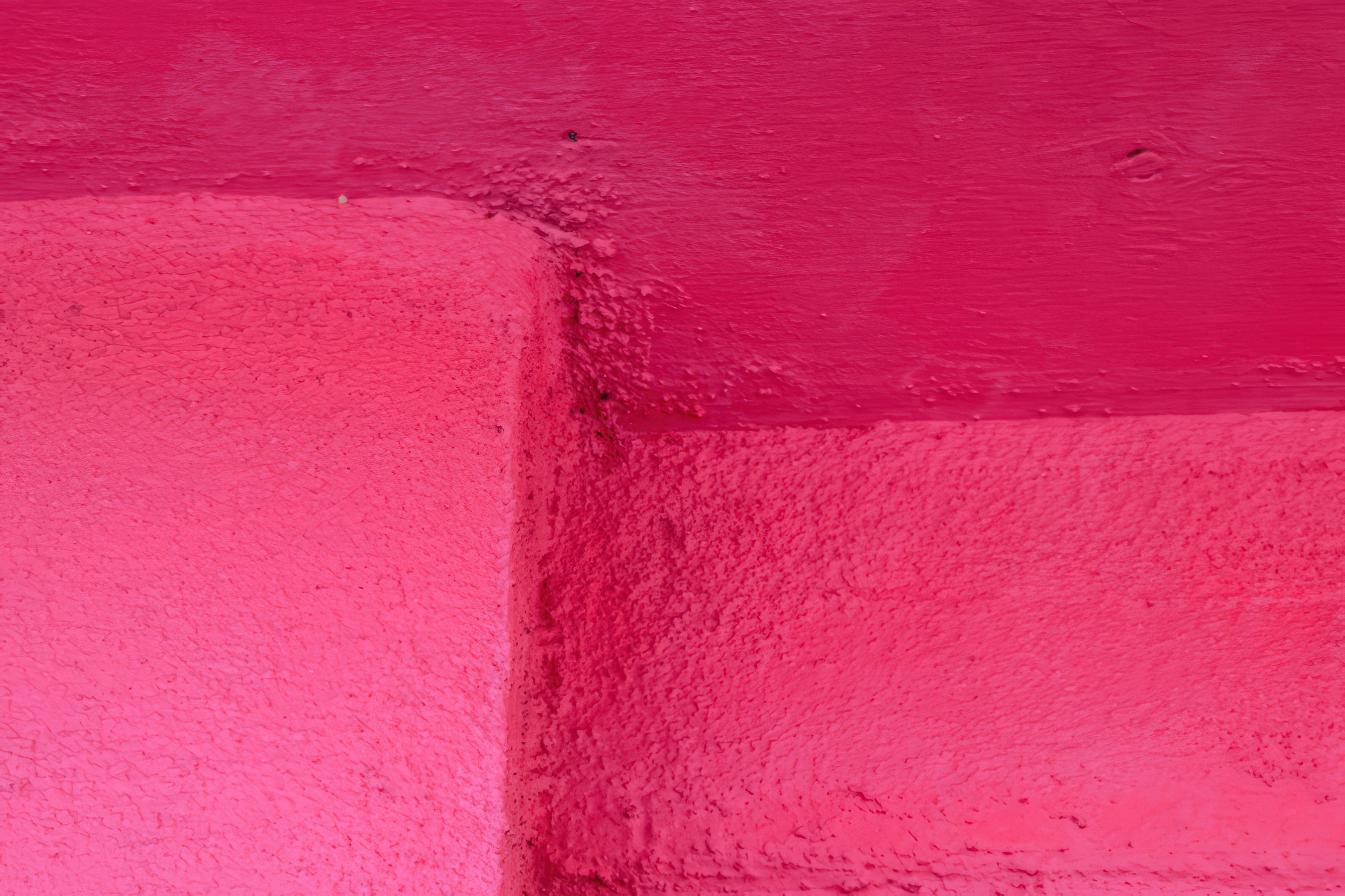 Una esquina de pared texturizada rosa con techo pintado.