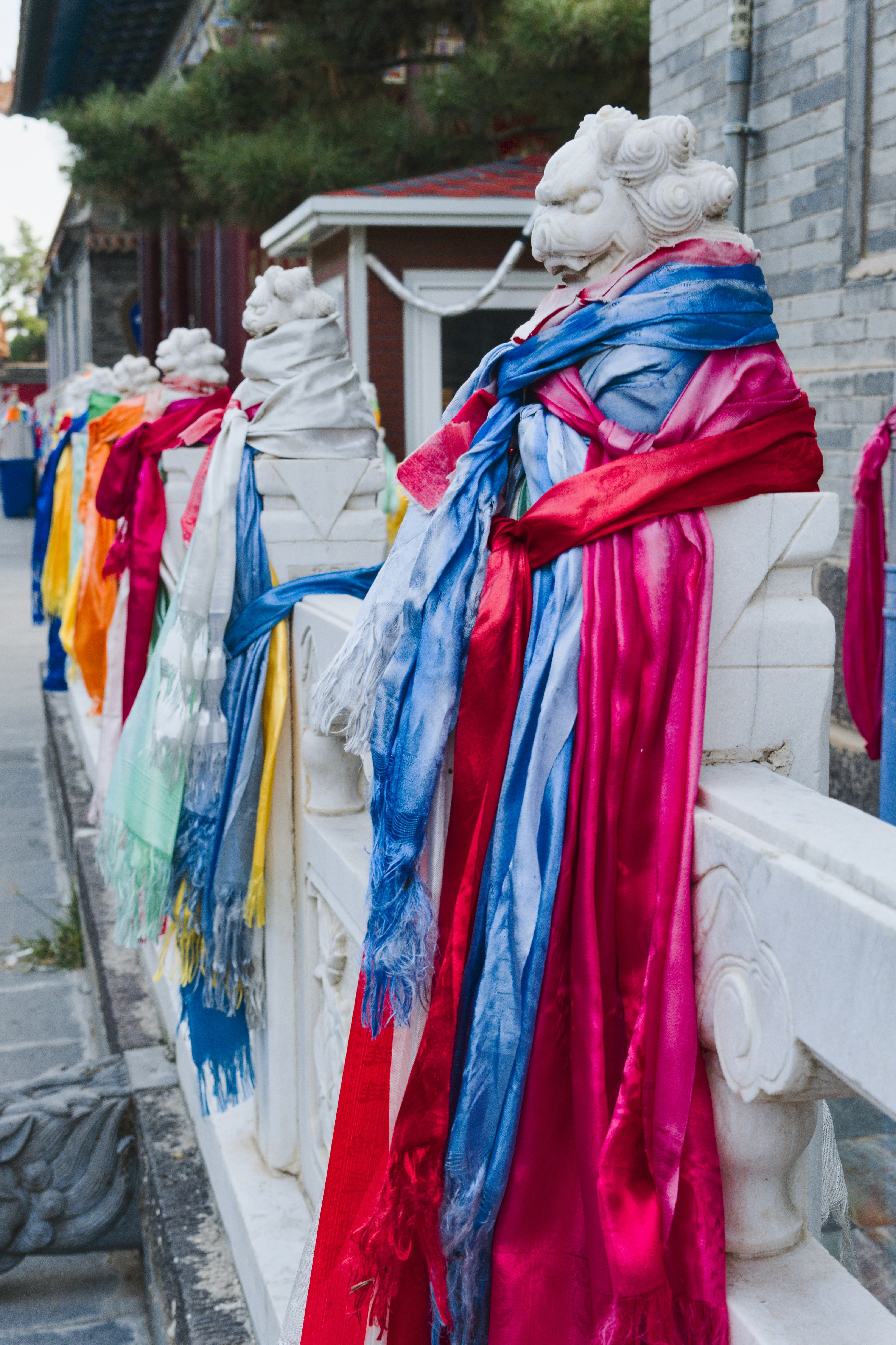 Colorful scarves draped on a stone railing with lion heads.