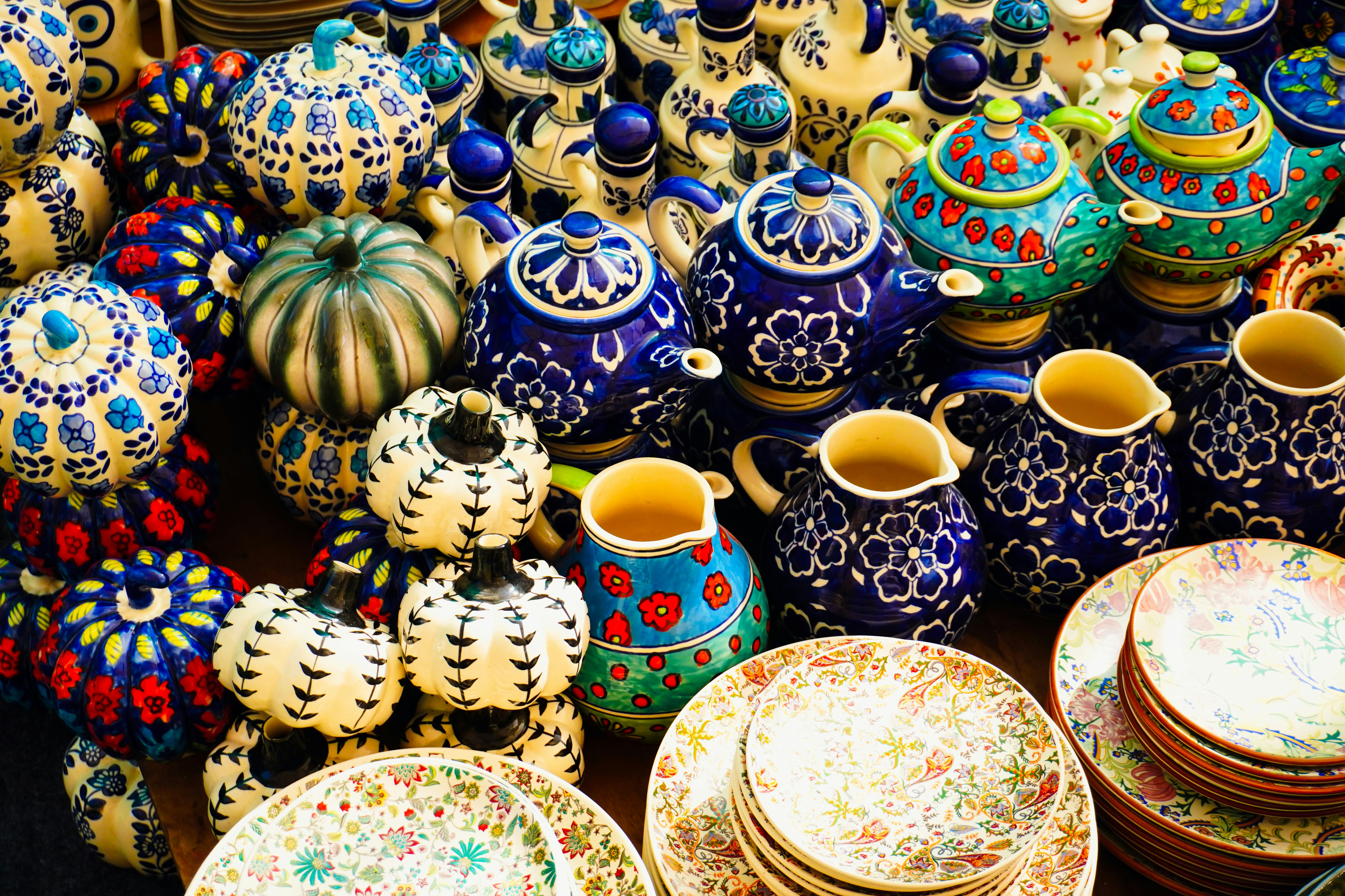 Colorful ceramic teapots and plates displayed at market.