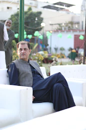 Man in vest and blue suit sitting on white couch