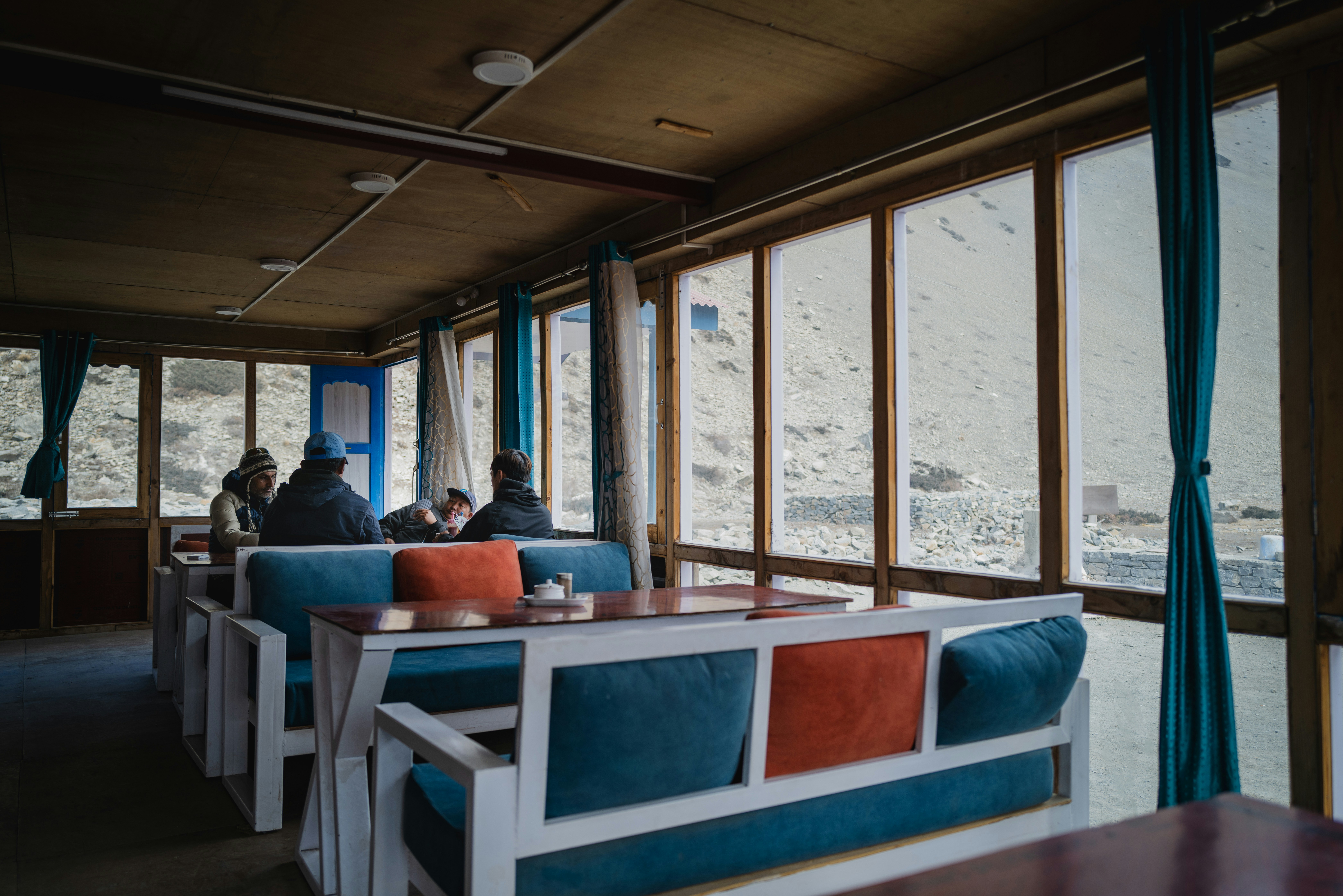People sitting in a cafe with large windows overlooking mountains.