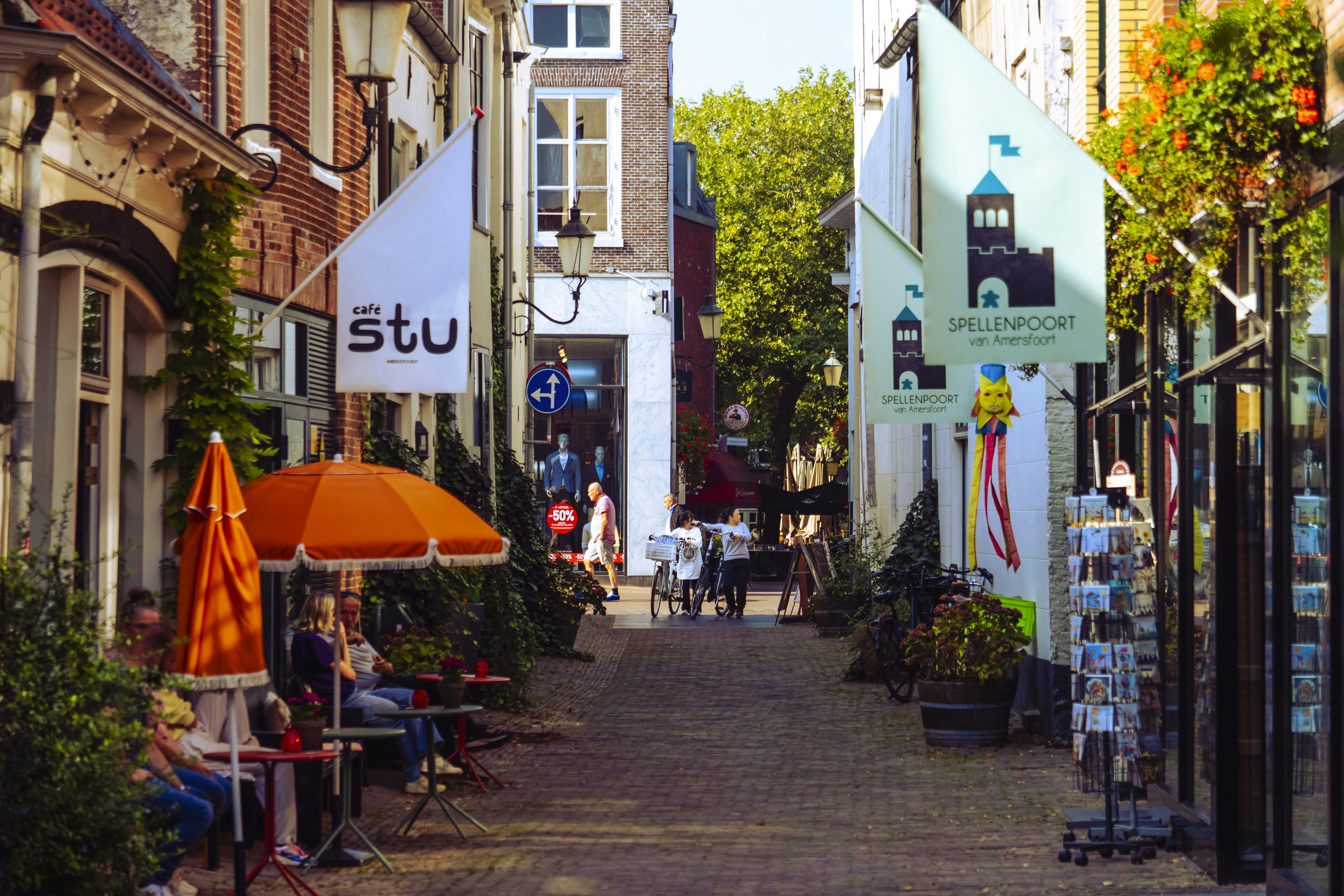 People sitting at outdoor cafe tables on a sunny street.