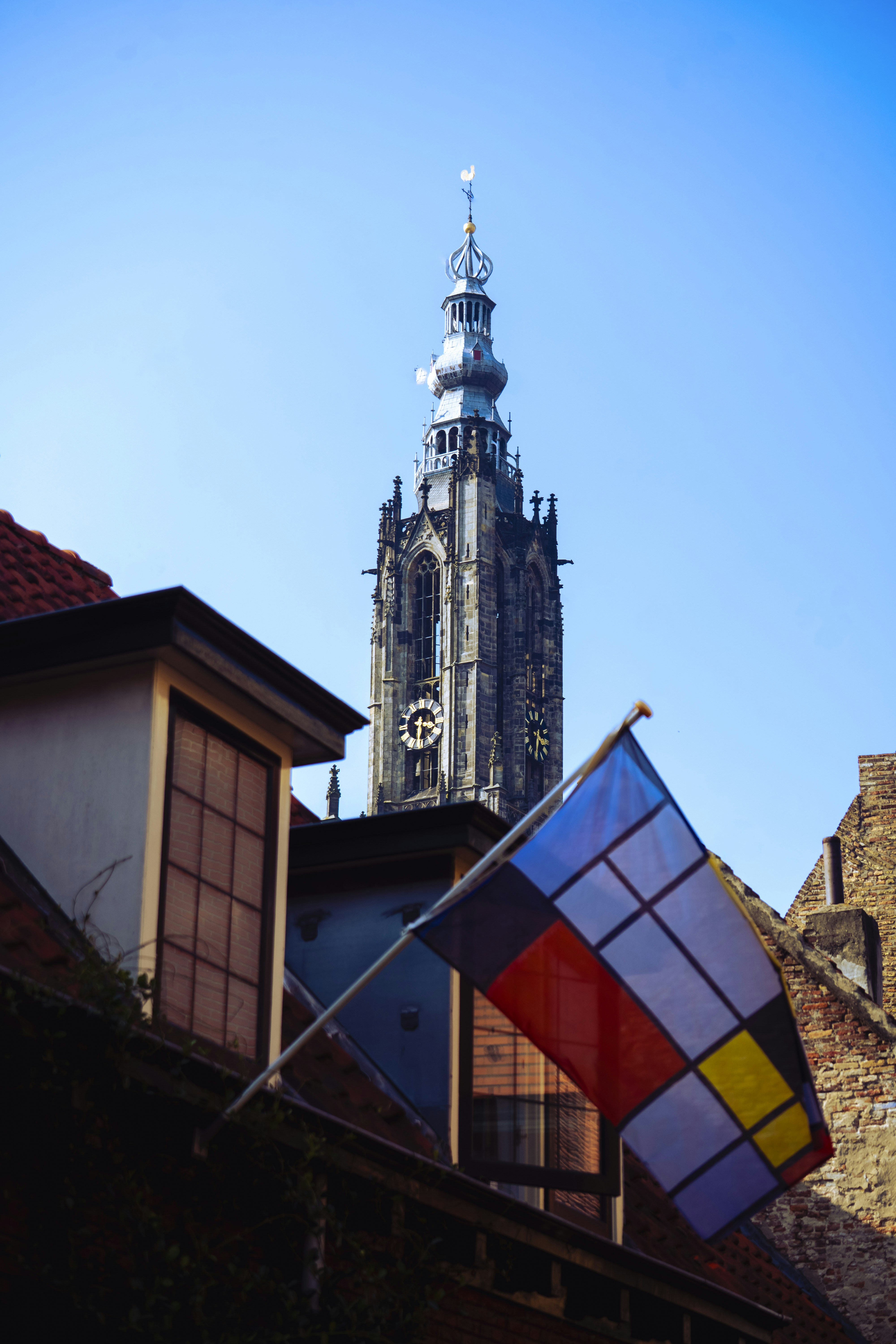 A tall church tower with a mondrian-style flag.