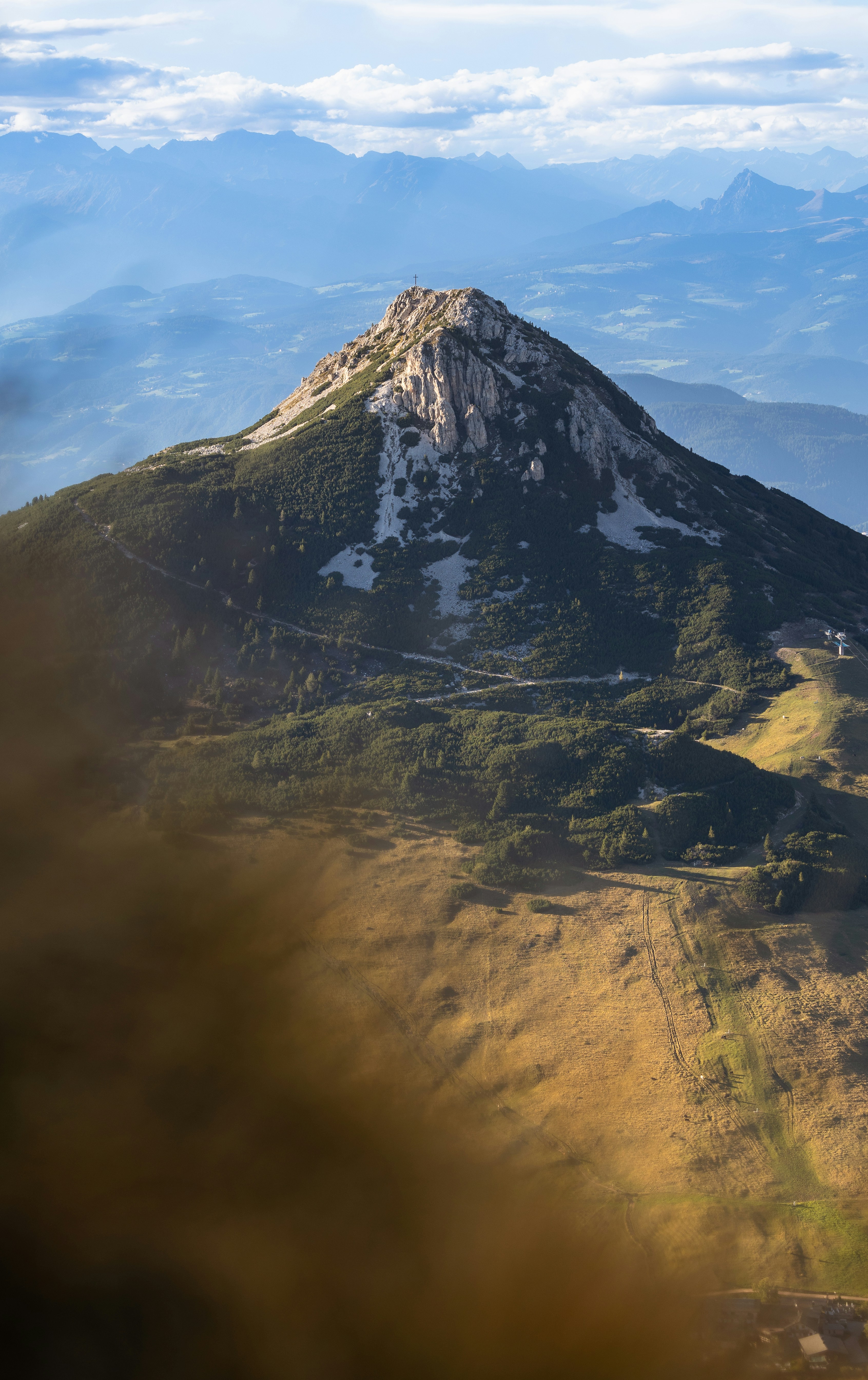 Jagged mountain peak with green slopes and distant layers.