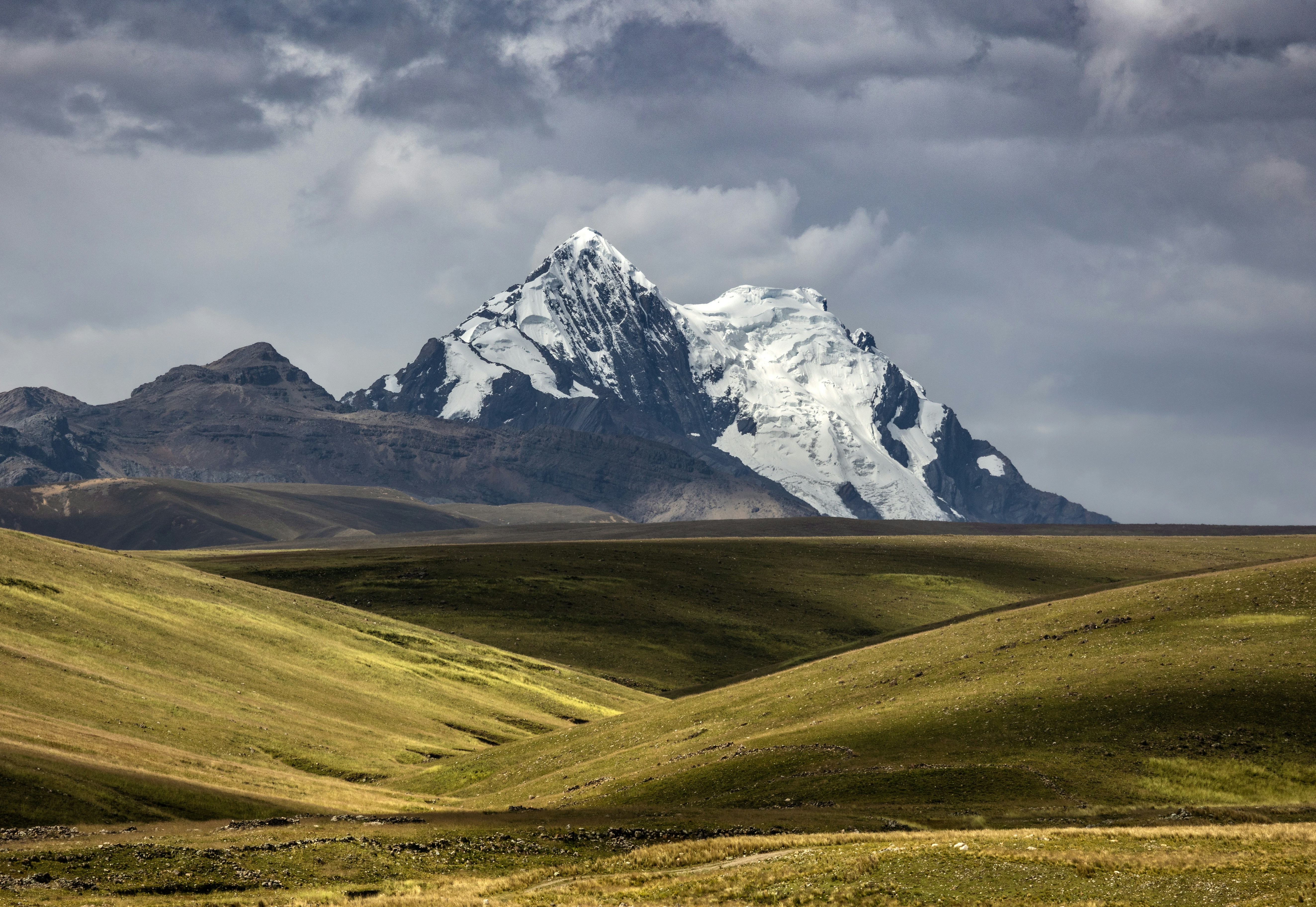 Snow-capped mountain peak under dramatic cloudy sky
