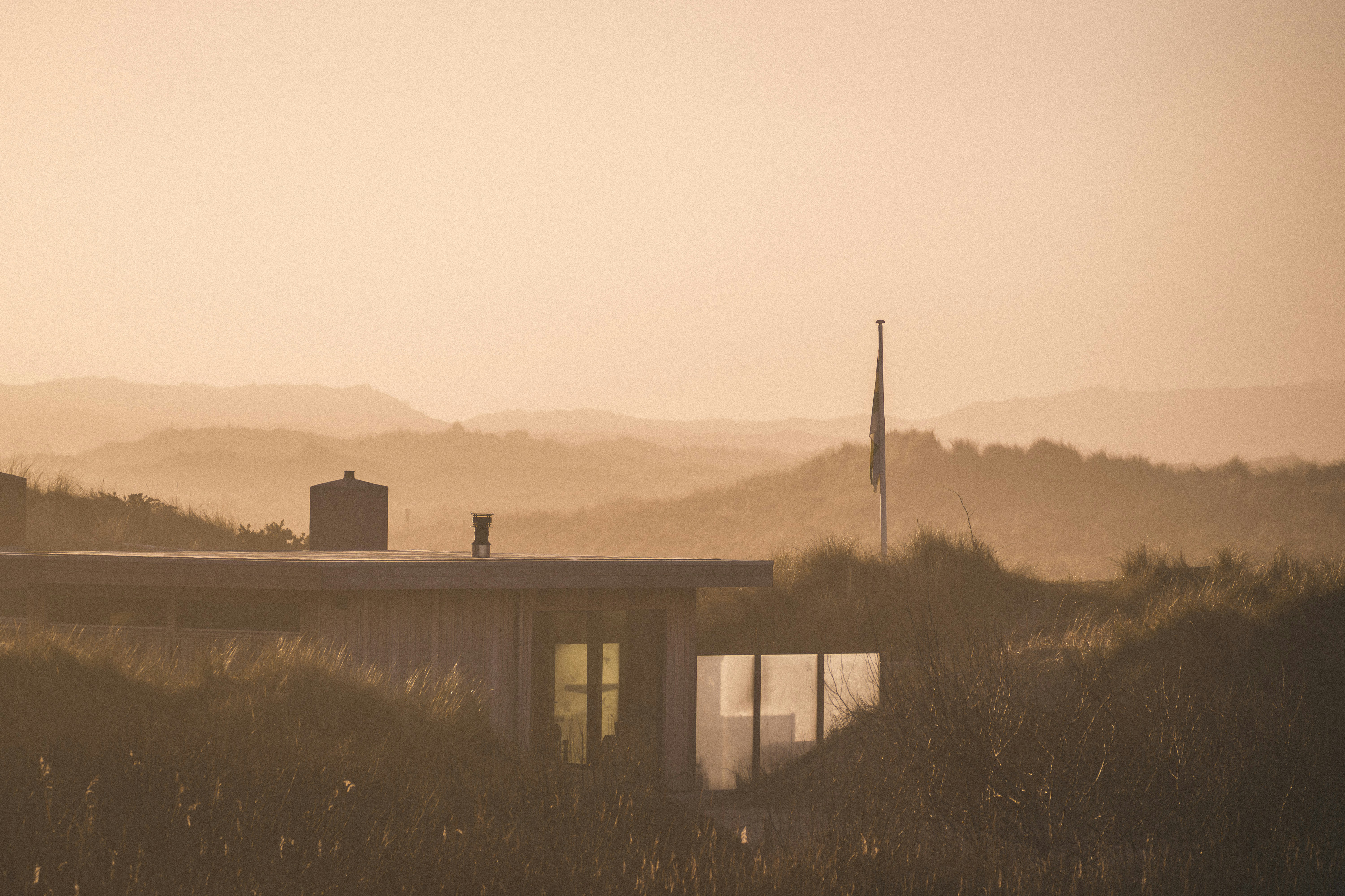 일몰 무렵 모래언덕 속에 자리 잡은 현대적인 집