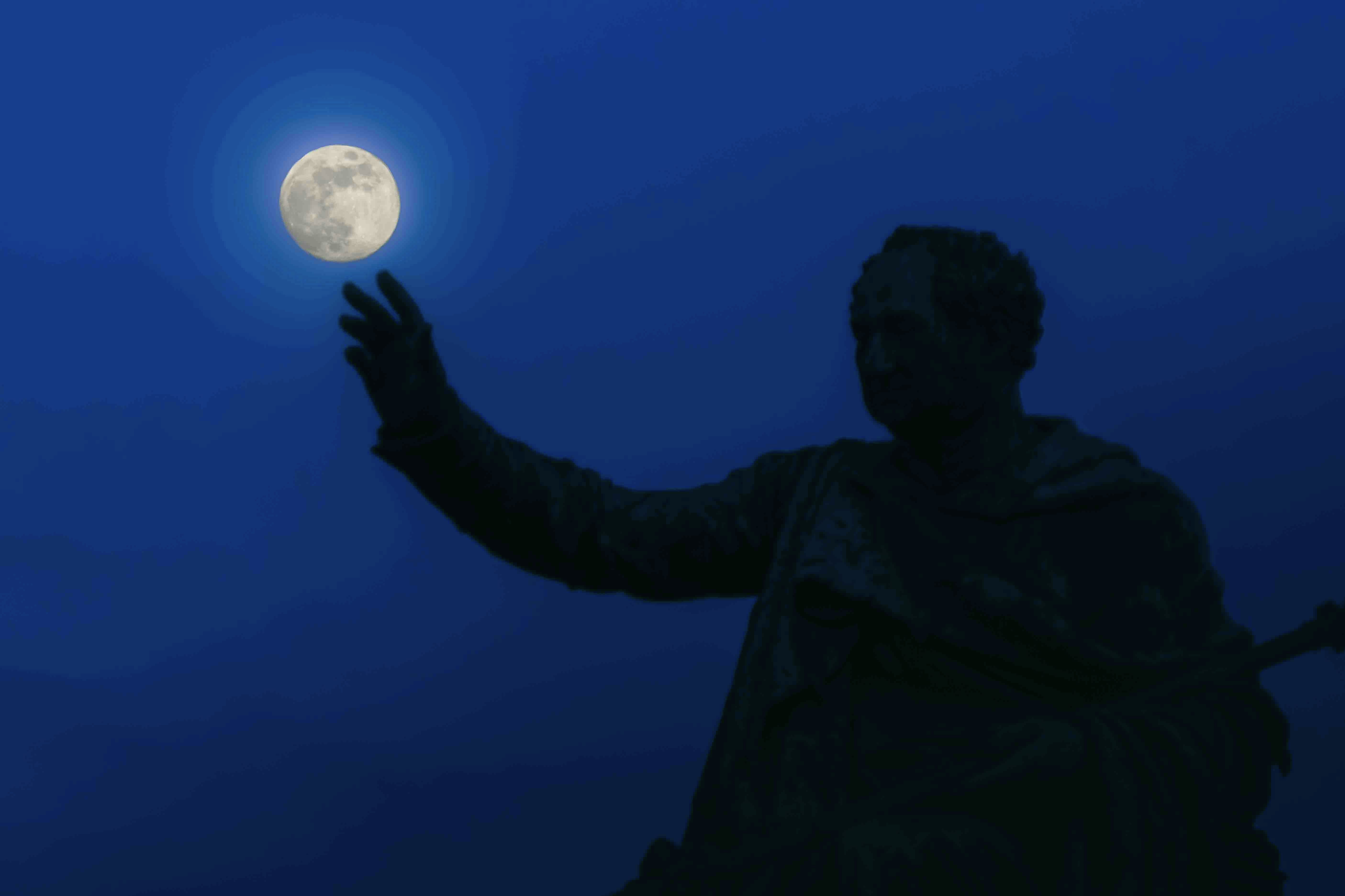 Silhouette of a person reaching for the moon