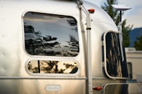 Silver airstream trailer reflecting trees and sky