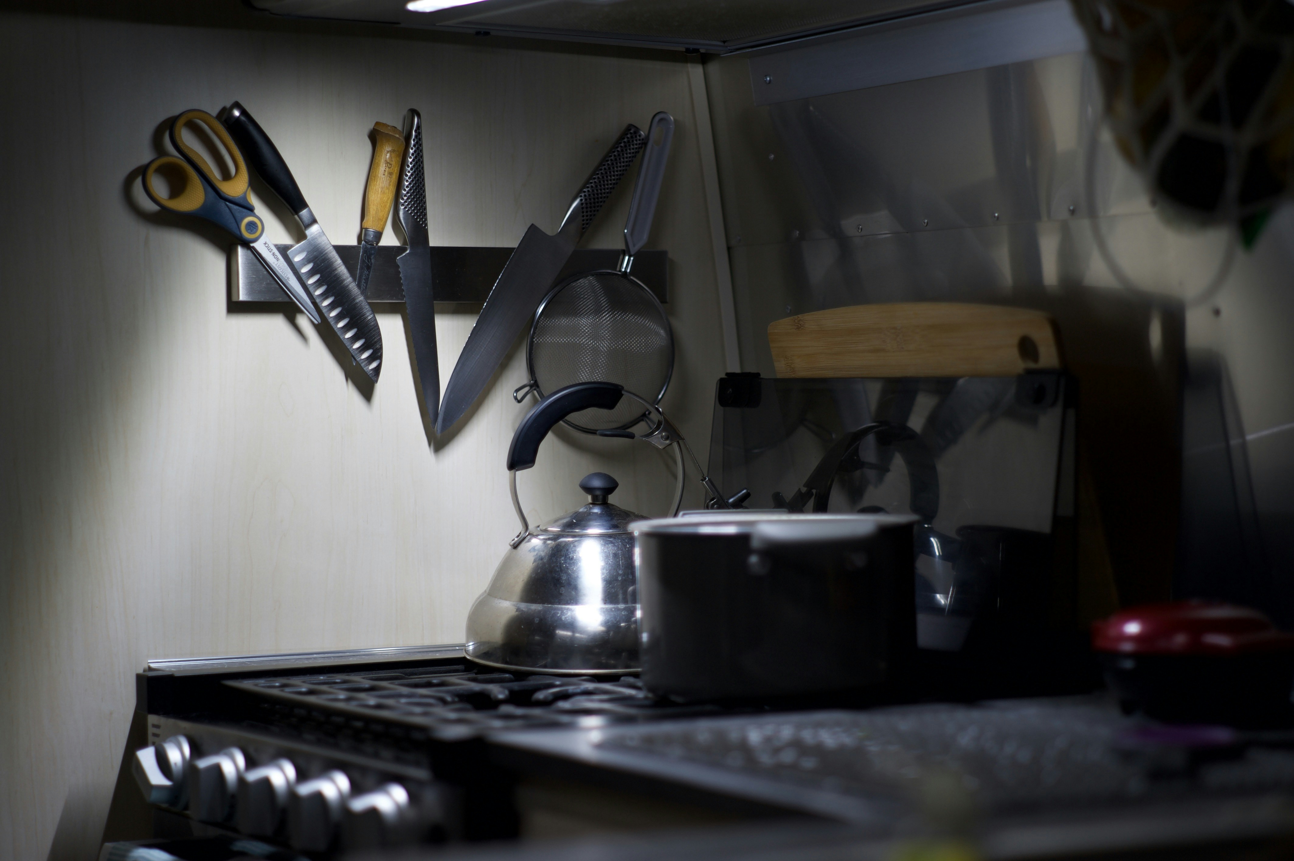 Kitchen counter with knives, scissors, and kettle.
