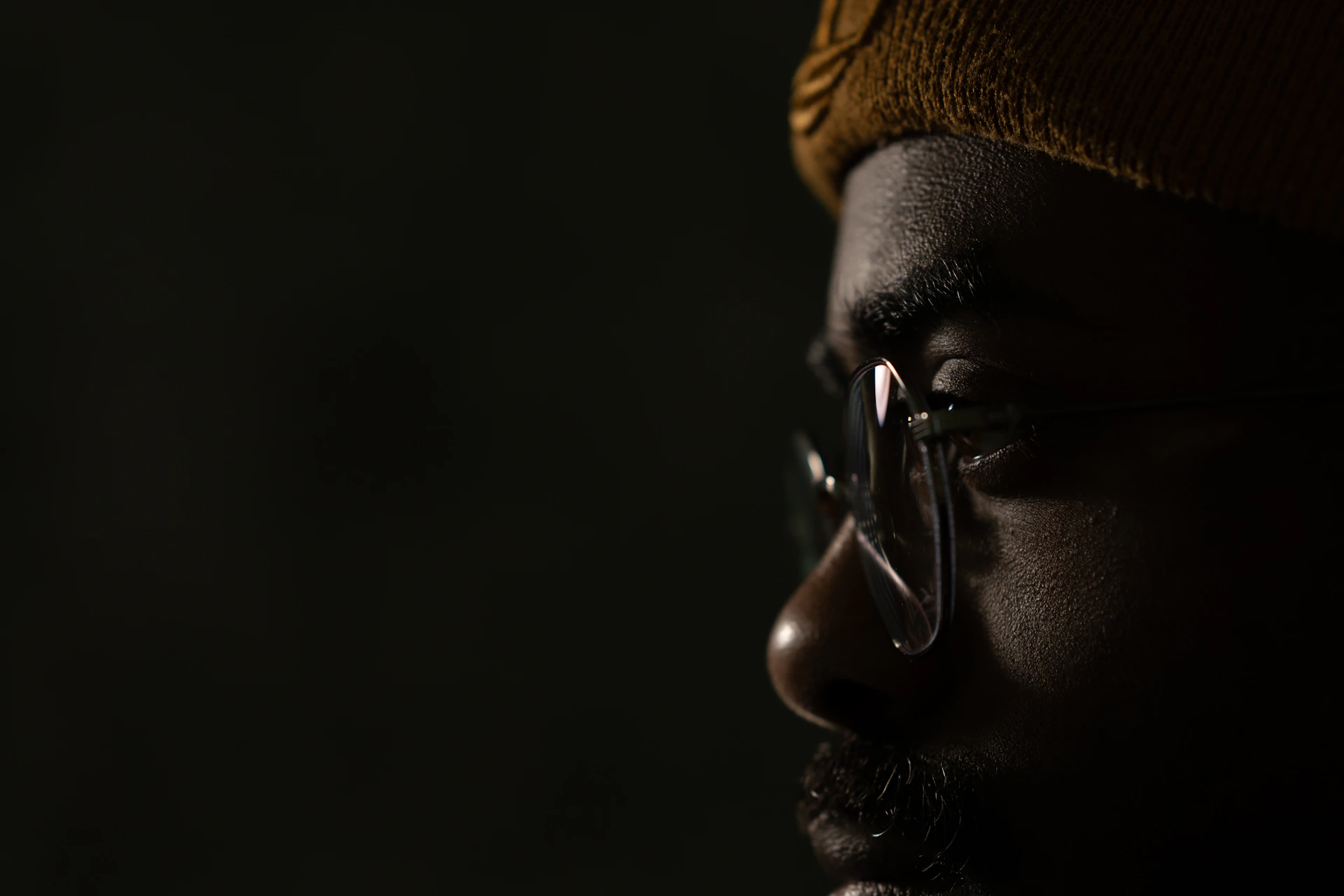 Close-up of a man wearing glasses and a hat.