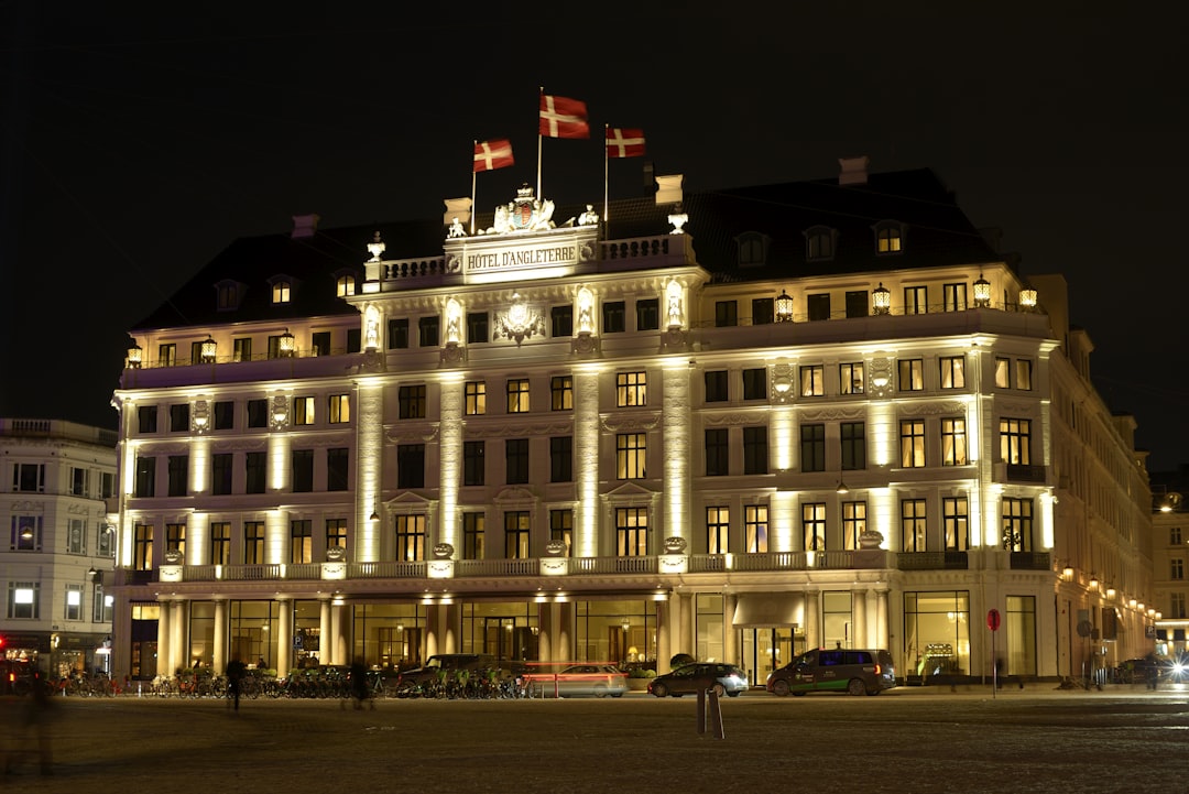 Grand hotel building illuminated at night with flags